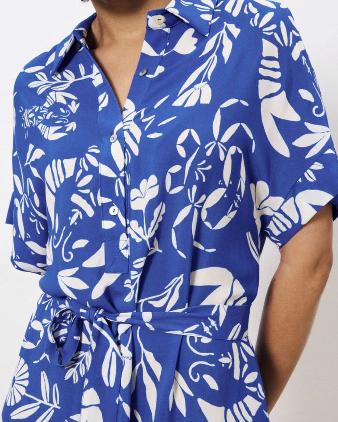 Blue and white floral patterned shirt worn by a person on a plain background