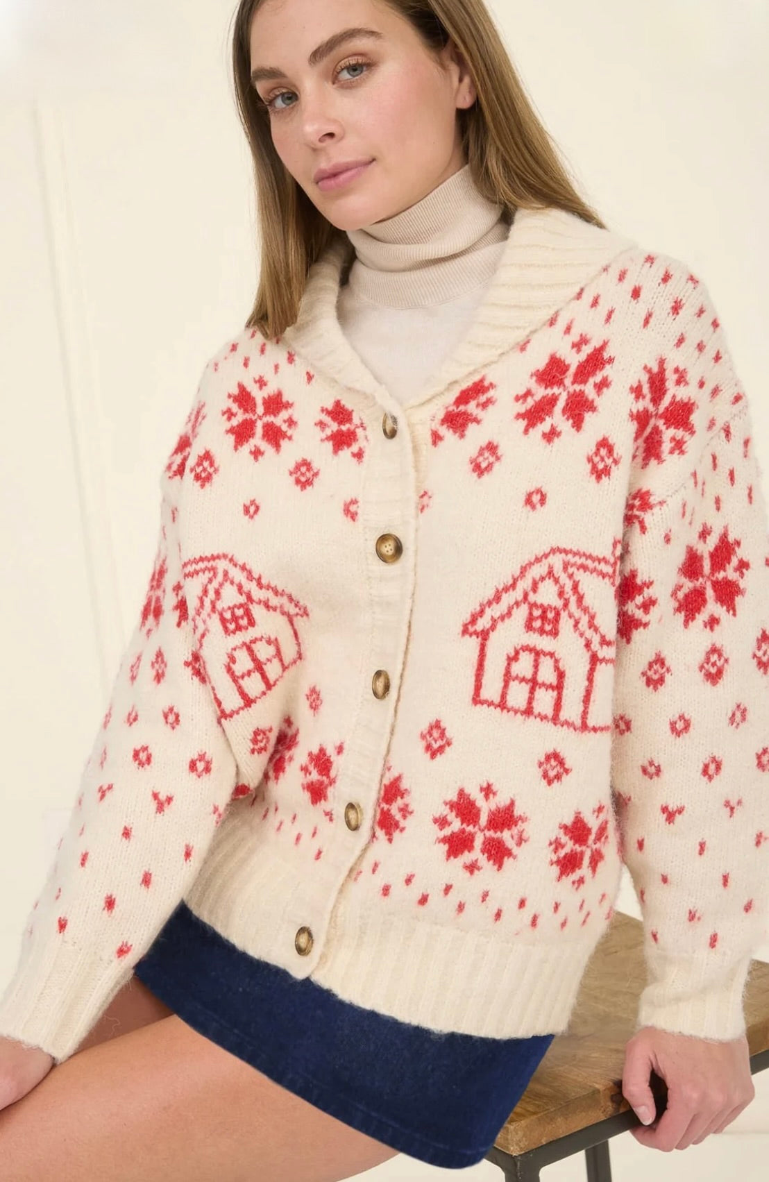 Woman wearing a cream cardigan with red floral and house patterns