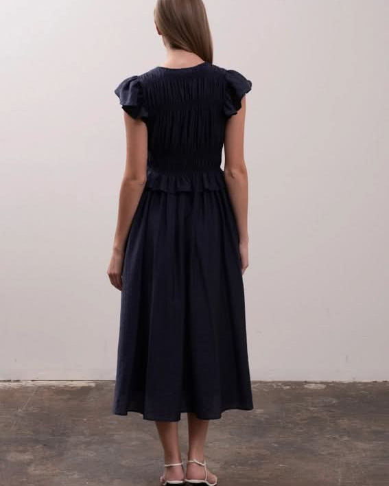 Woman wearing a black dress with puffed sleeves Moon River Shirred Ruffle Midi Dress