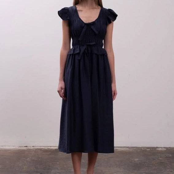 Woman wearing a dark blue dress Moon River Shirred Ruffle Midi Dress