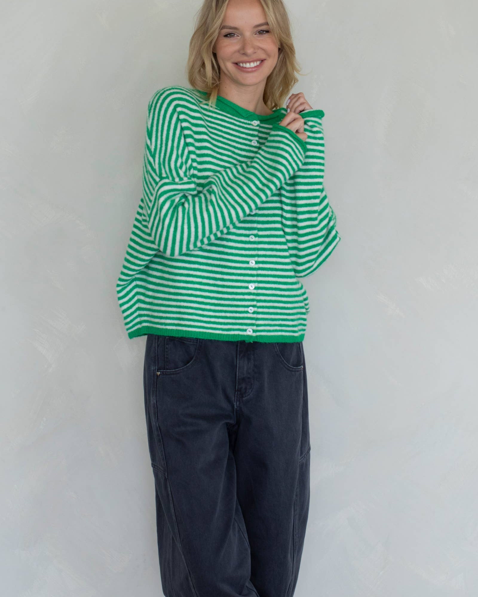 Person wearing a green and white striped sweater and dark pants