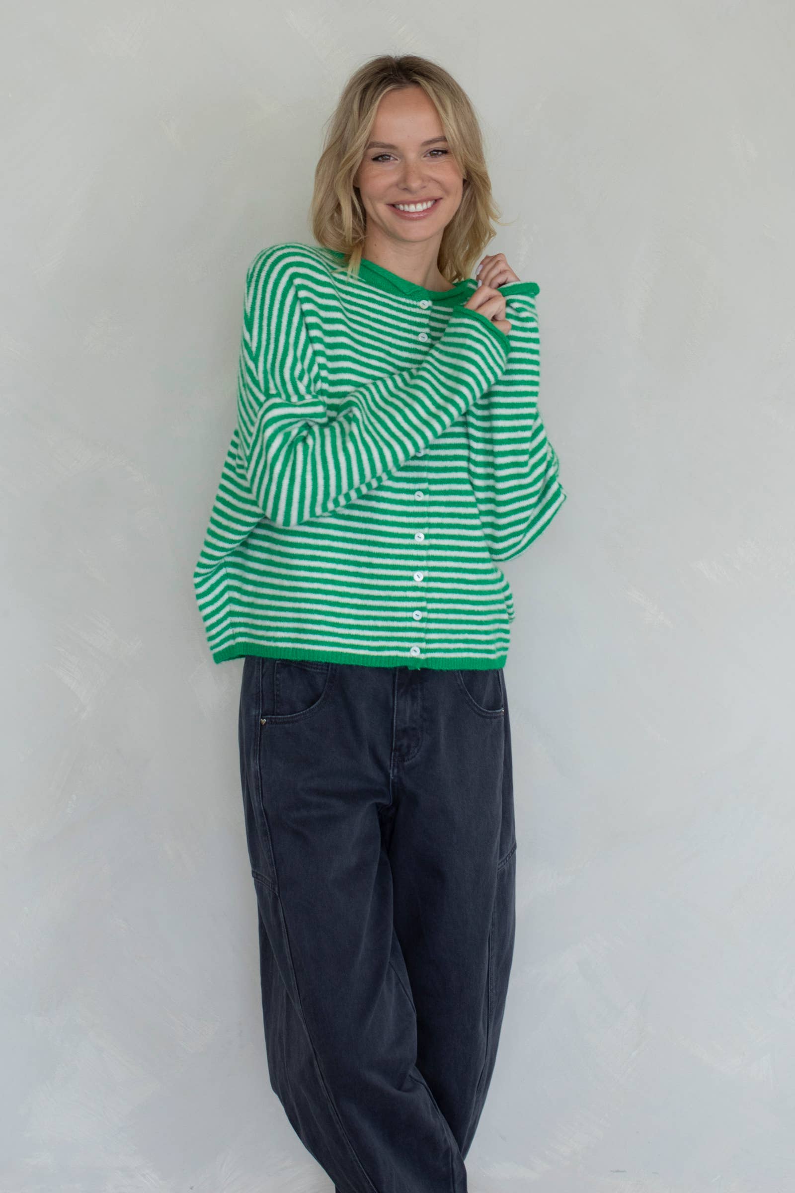 Person wearing a green and white striped sweater and dark pants