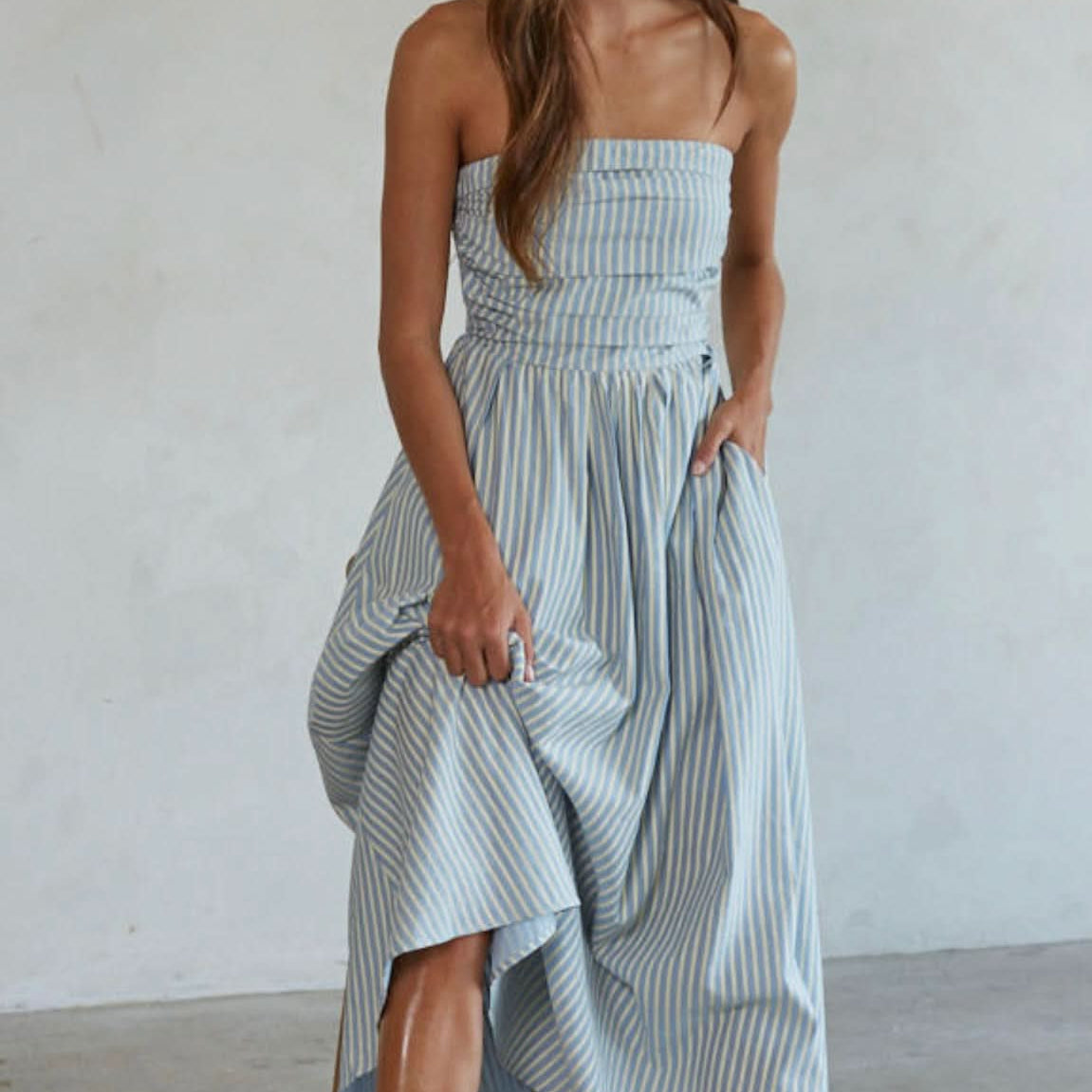 Woman wearing white and blue vertically striped, sleeveless maxi dress s