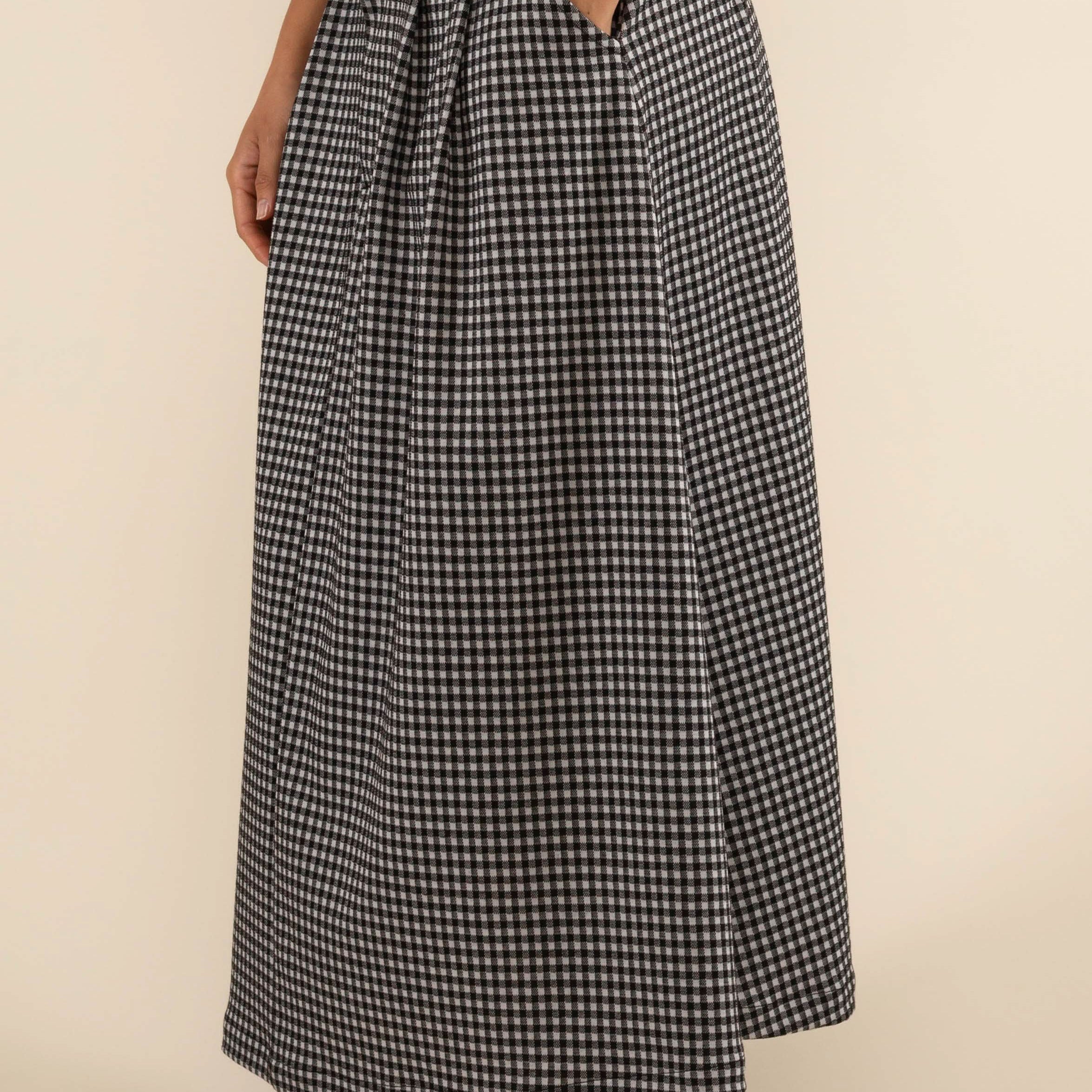 Person wearing checkered skirt with pleats at the front and side pockets.