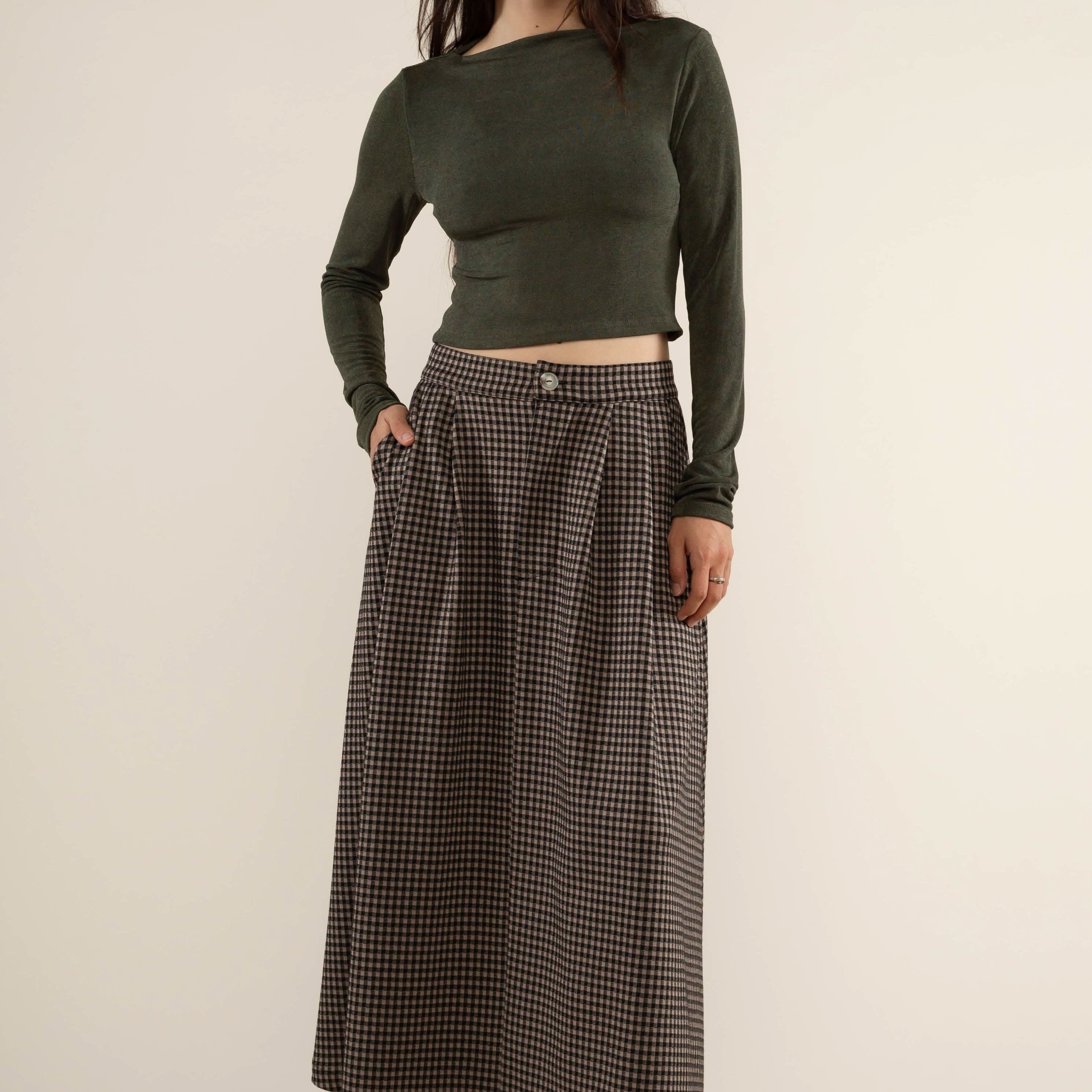 Woman wearing a green long-sleeve top and plaid skirt gray