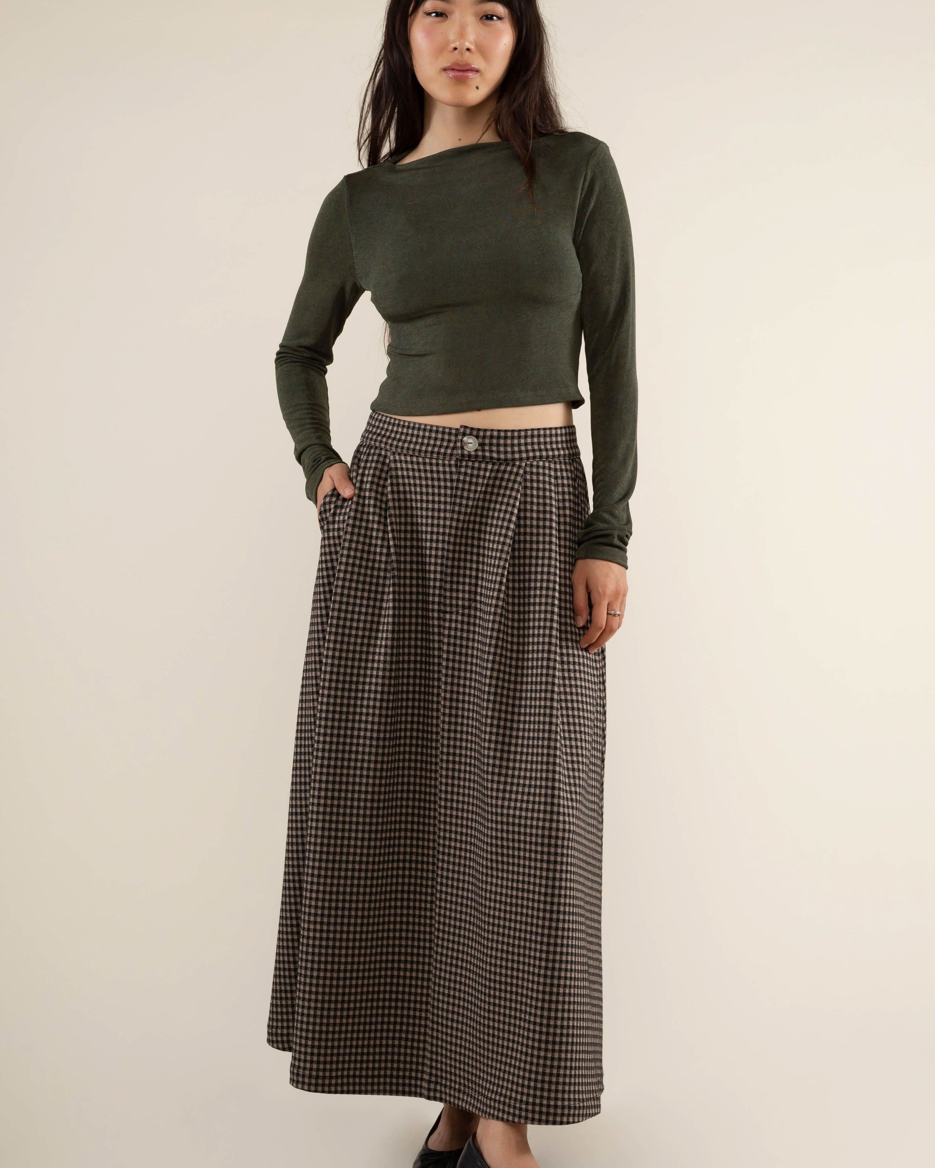 Woman wearing a green long-sleeve top and plaid skirt gray
