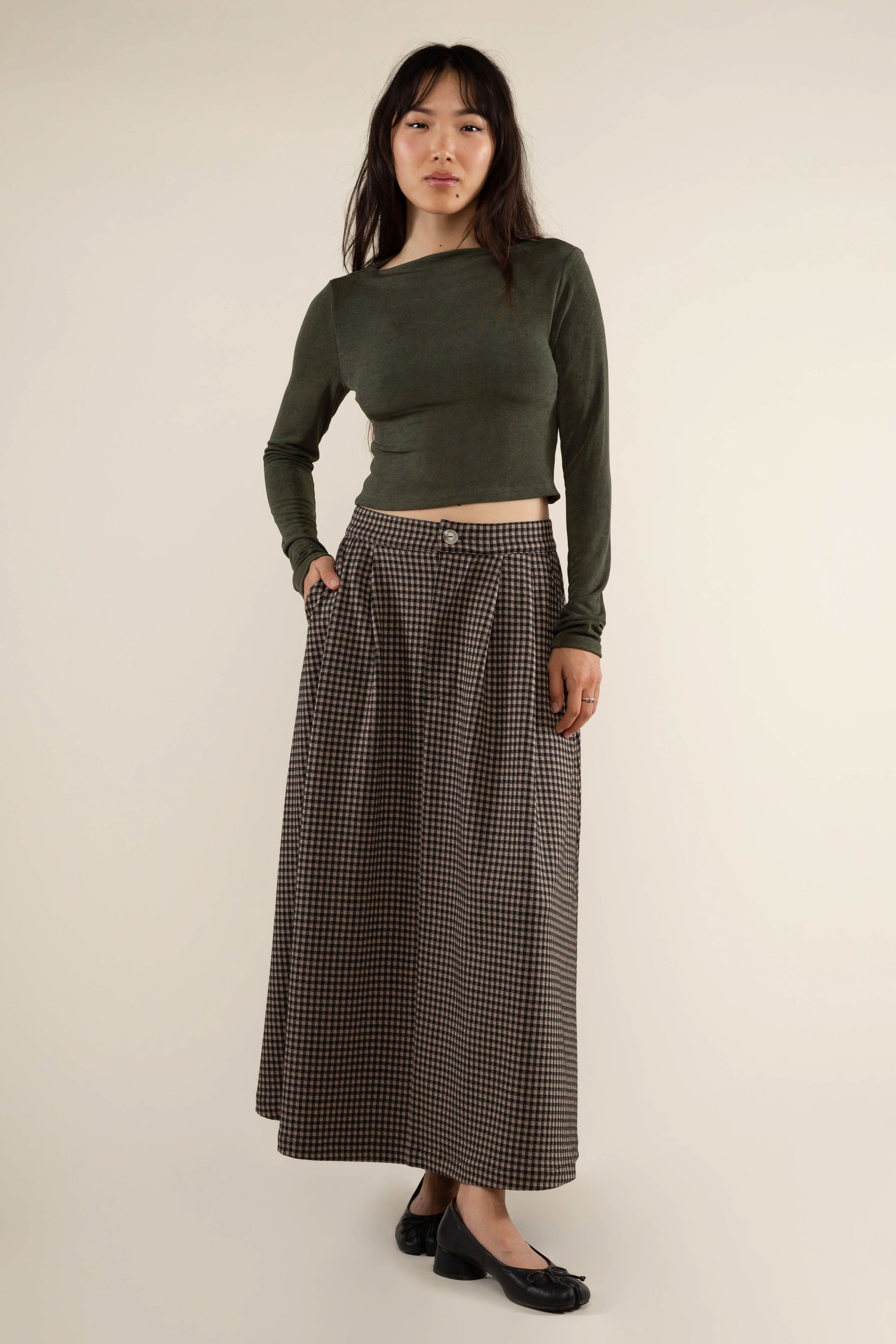 Woman wearing a green long-sleeve top and plaid skirt gray