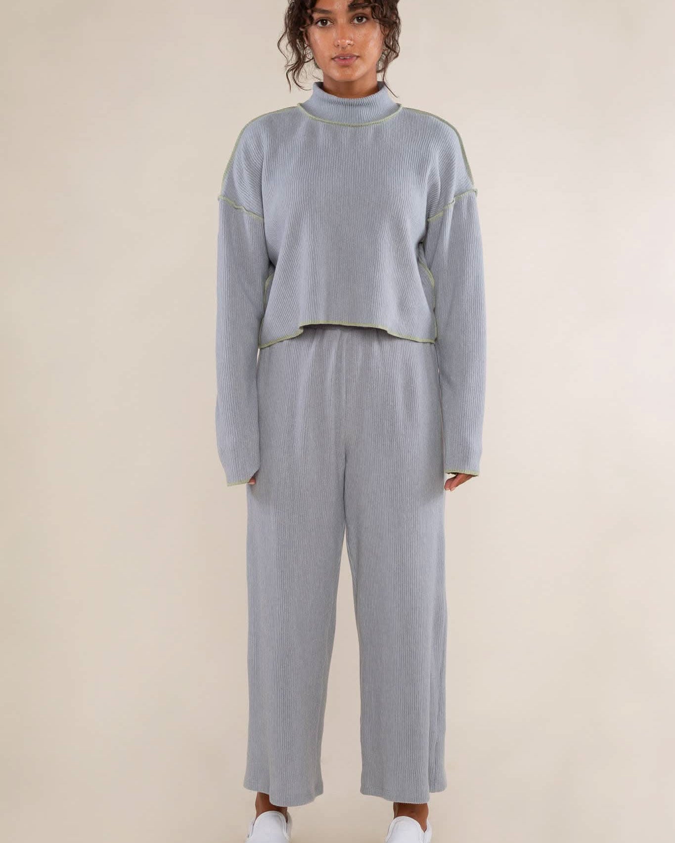Person wearing a light gray cropped turtleneck top features delicate pleats