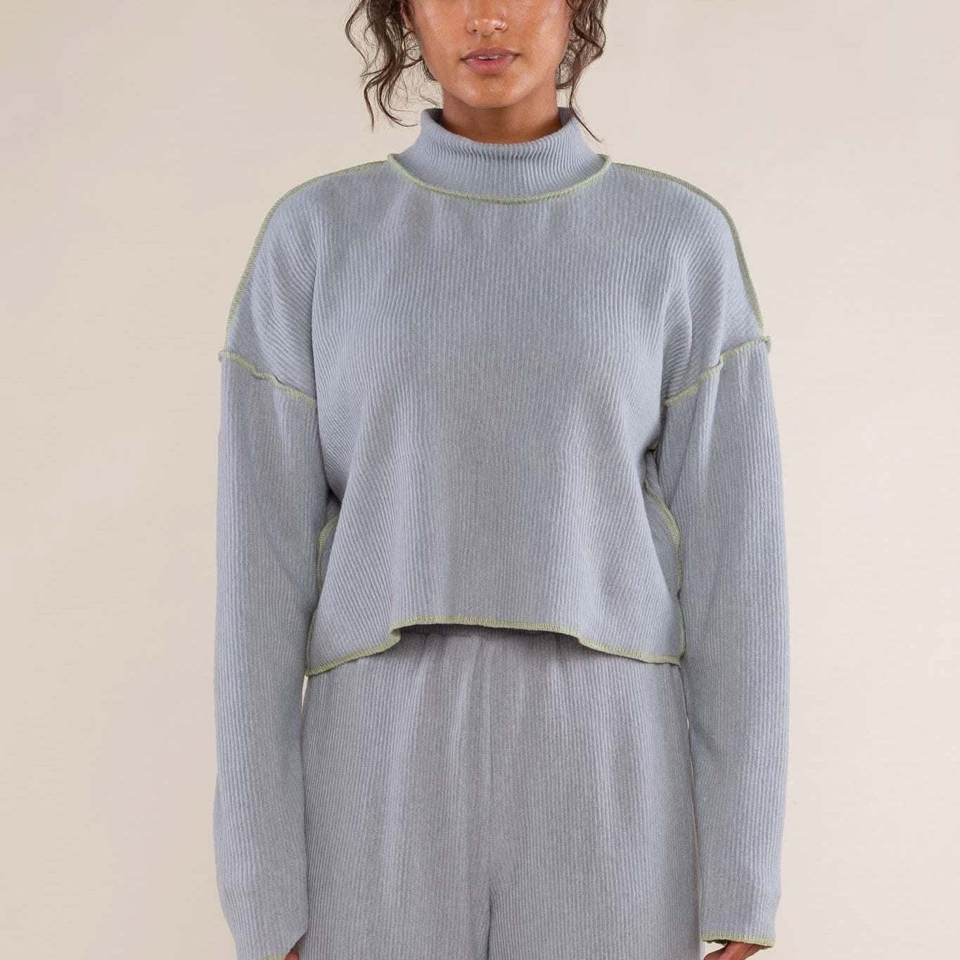 Woman wearing a light blue ribbed sweater and pants