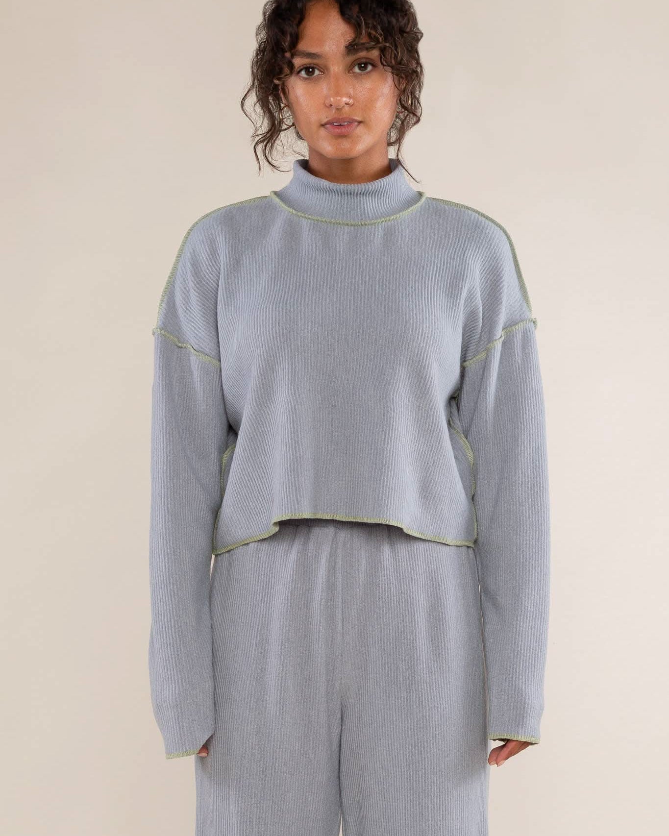 Woman wearing a light blue ribbed sweater and pants