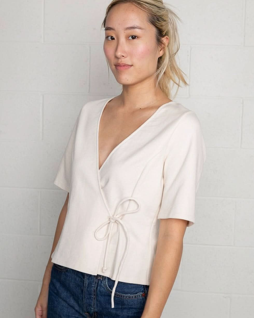 Woman wearing a cream wrap short sleeve shirt with blue jeans