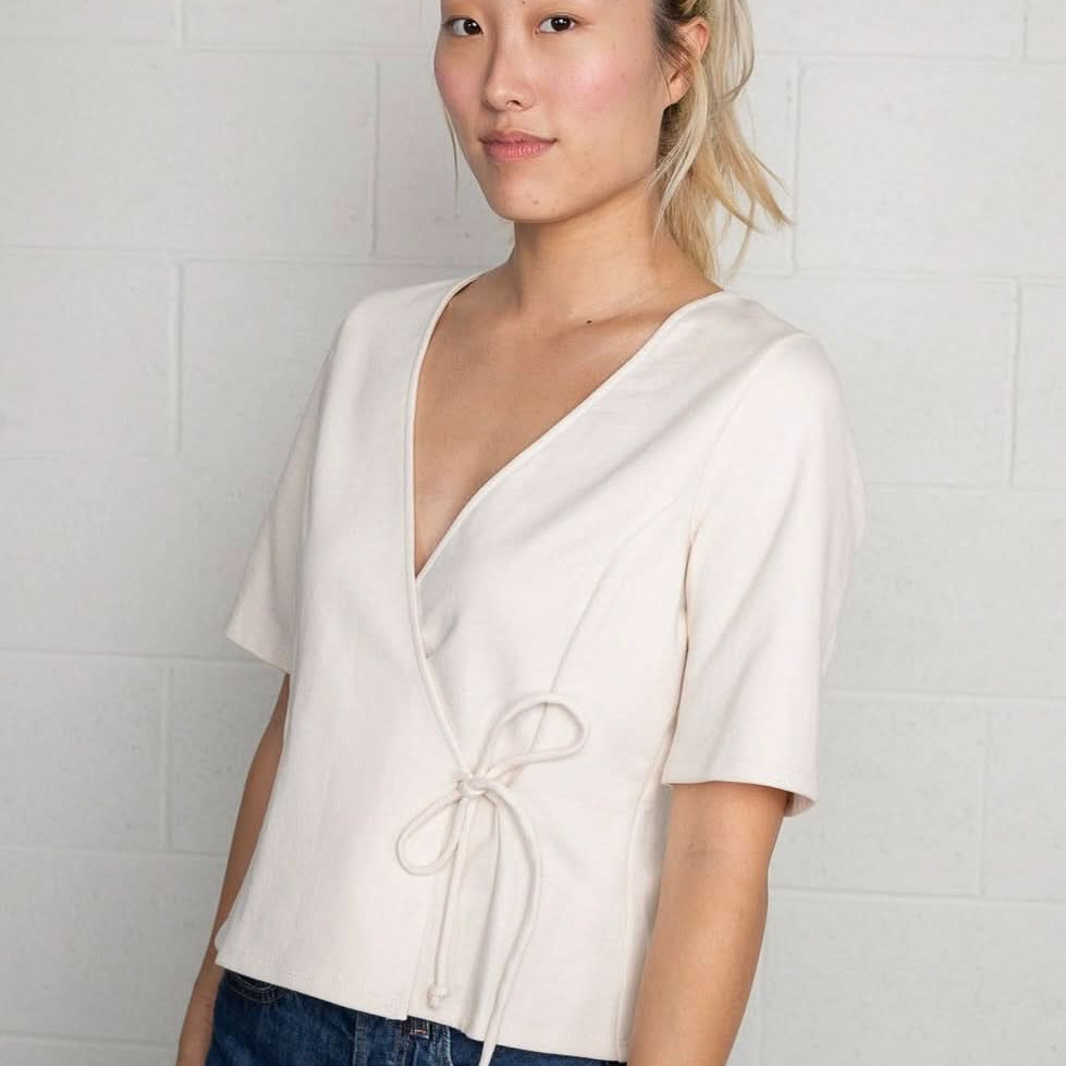 Woman wearing a cream wrap short sleeve shirt with blue jeans