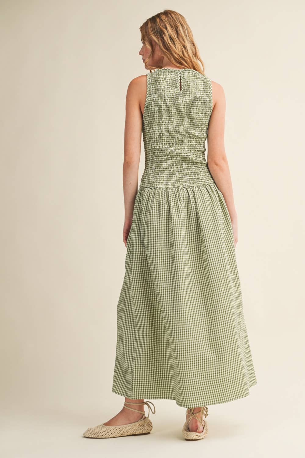 Woman wearing a green checkered dress on a beige background