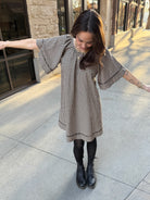 Woman standing outside wearing Vintage style babydoll dress black and tan gingham pattern with lace details 