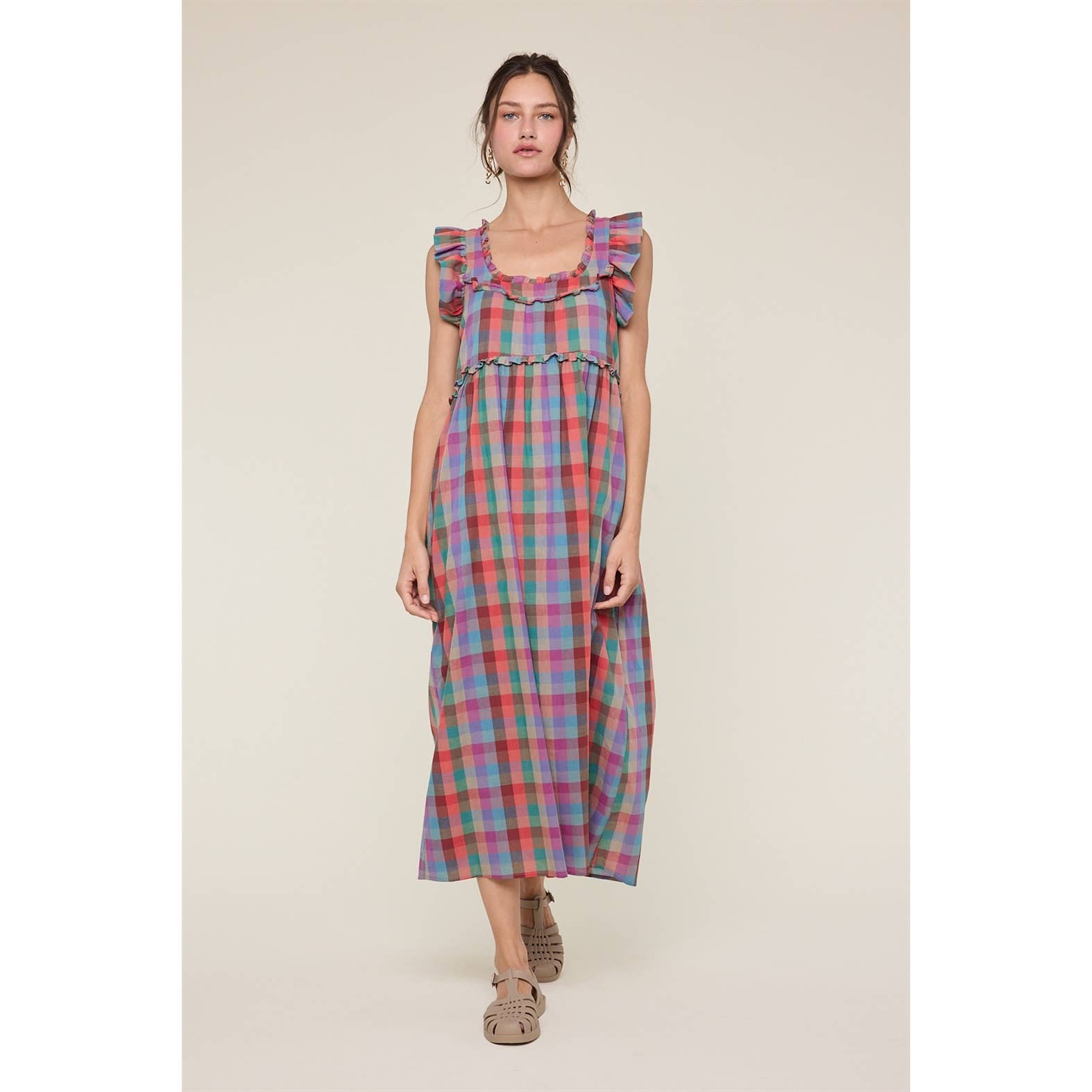 Woman wearing a colorful plaid dress on a beige background