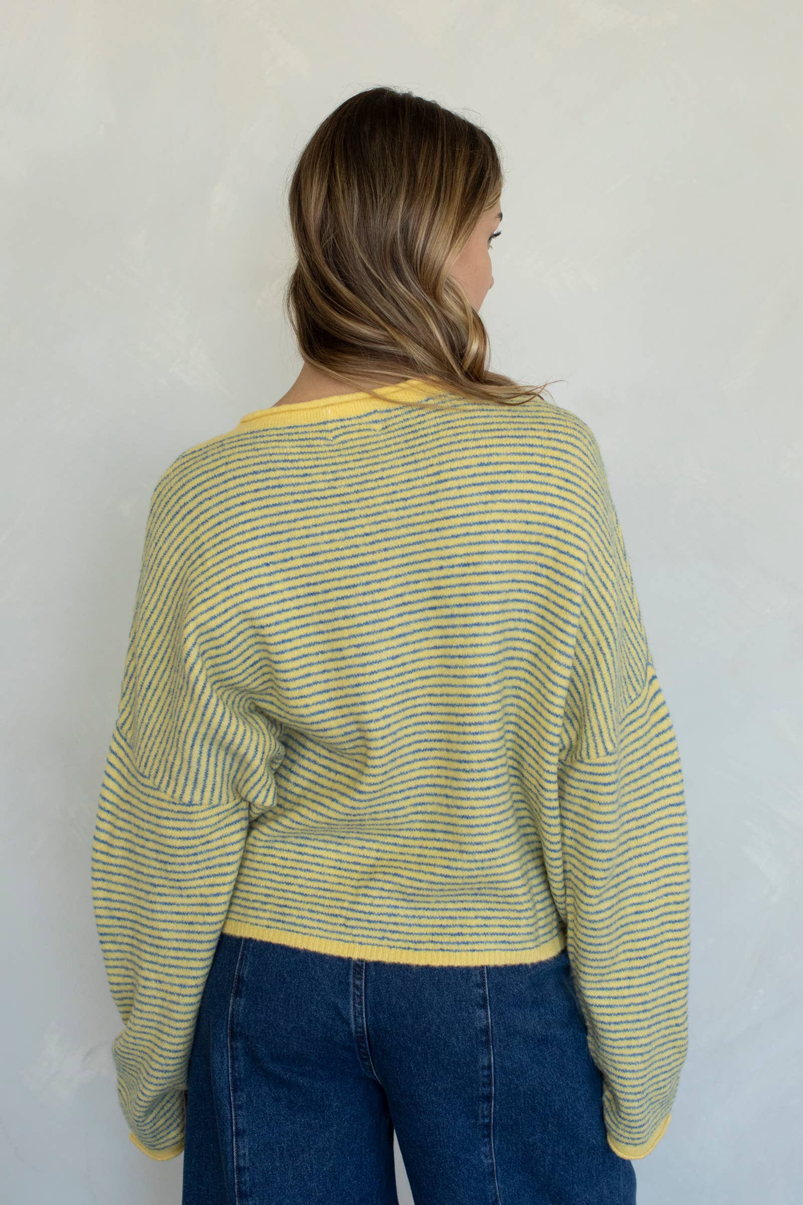 Woman wearing a green and yellow striped sweater against a white wall