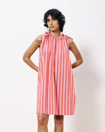 Woman wearing red and pink striped short dress with adjustable shoulder ties and a fluid fabric