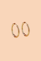  the everyday gold Huggies medium sized hoops on a pink peach background 