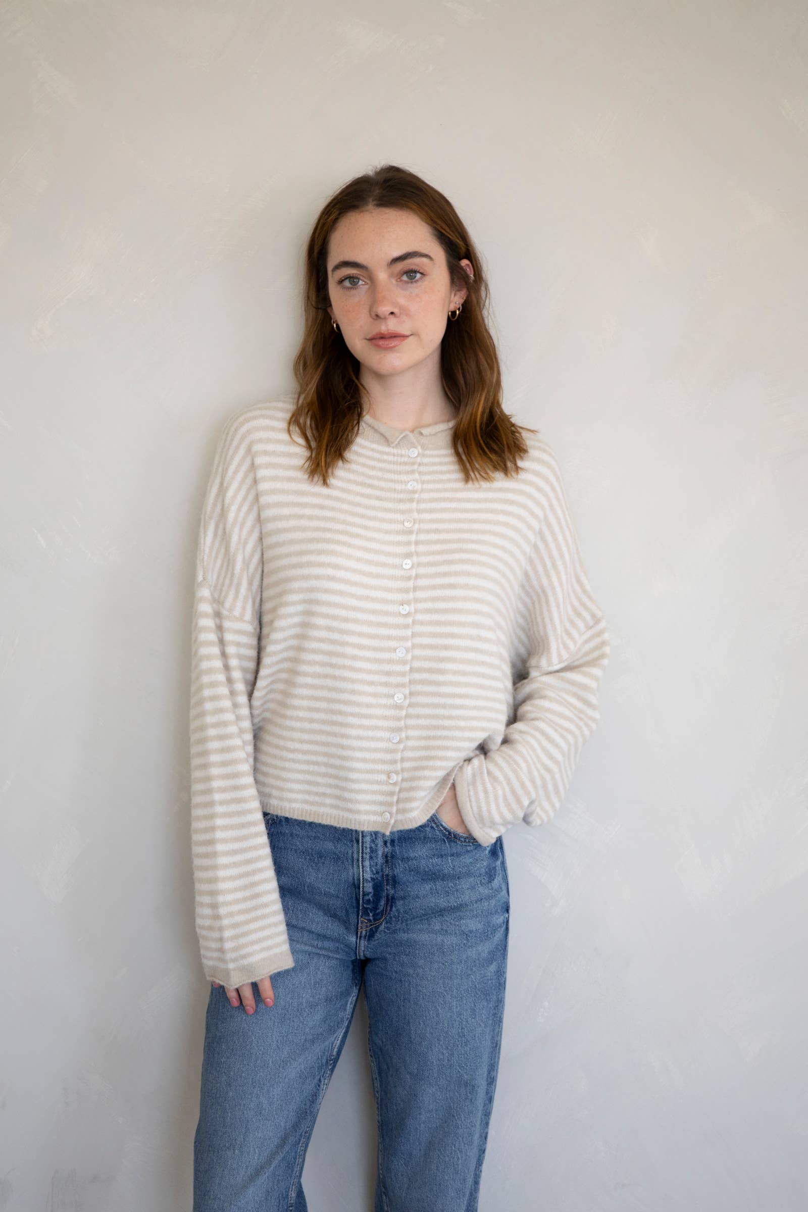 Woman wearing a striped sweater and jeans against a plain background