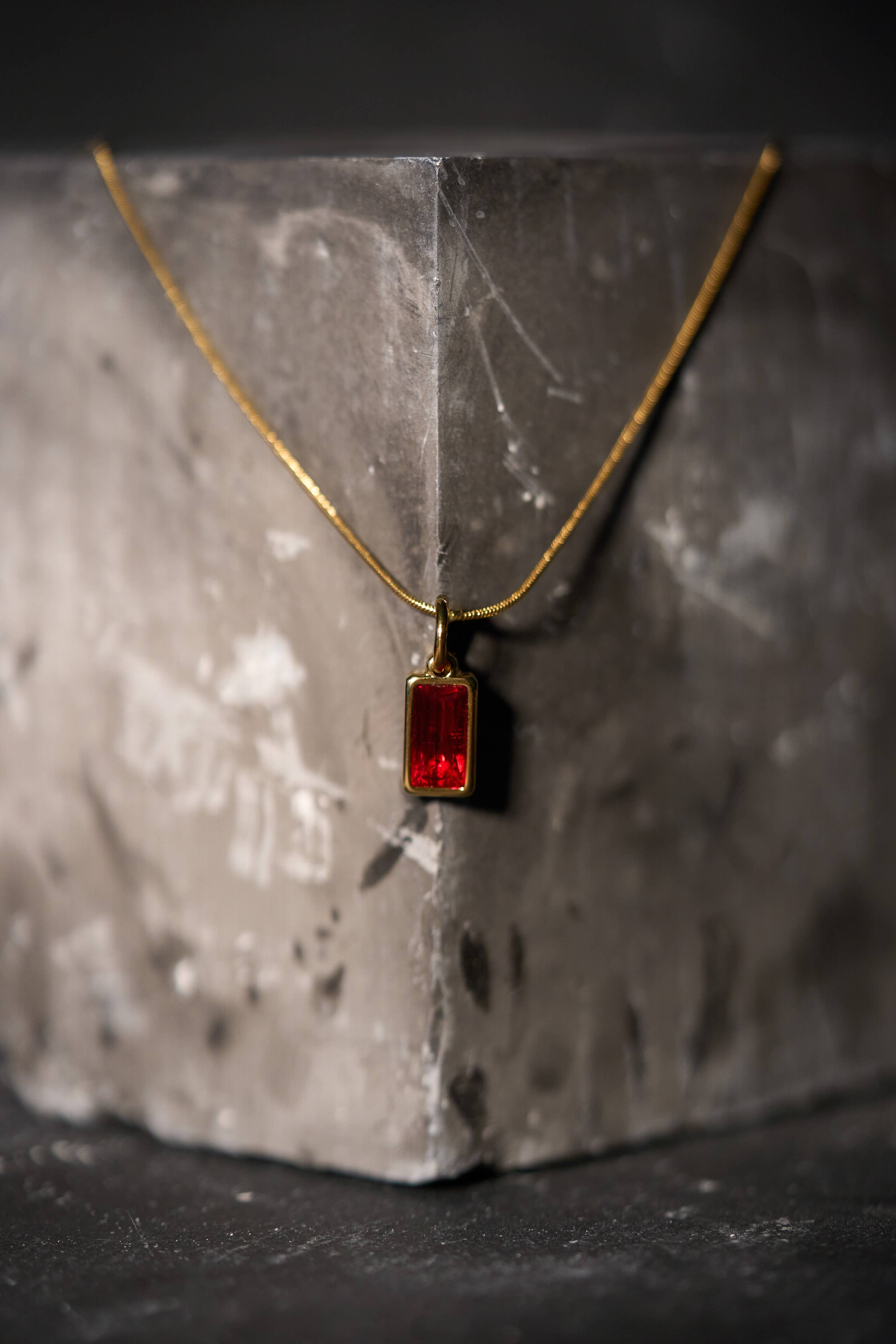 Gold necklace with a rectangular red gemstone pendant