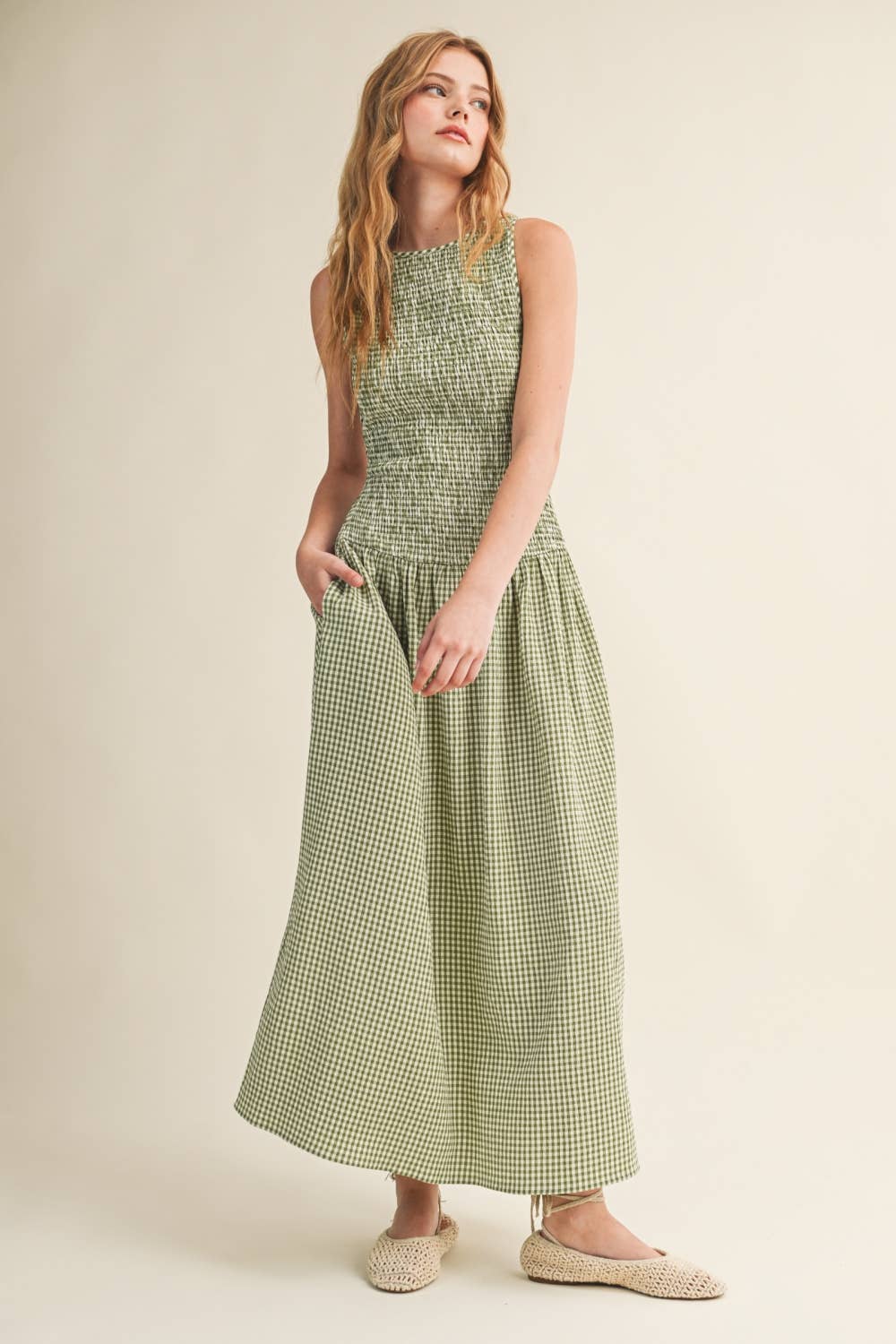 Woman wearing a green checkered dress against a beige background