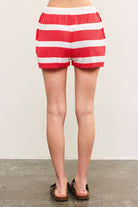 Woman wearing sandles and red and white horizontally striped waist sweater shorts with red drawstring tie 