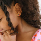 Child wearing strawberry flat back earrings 