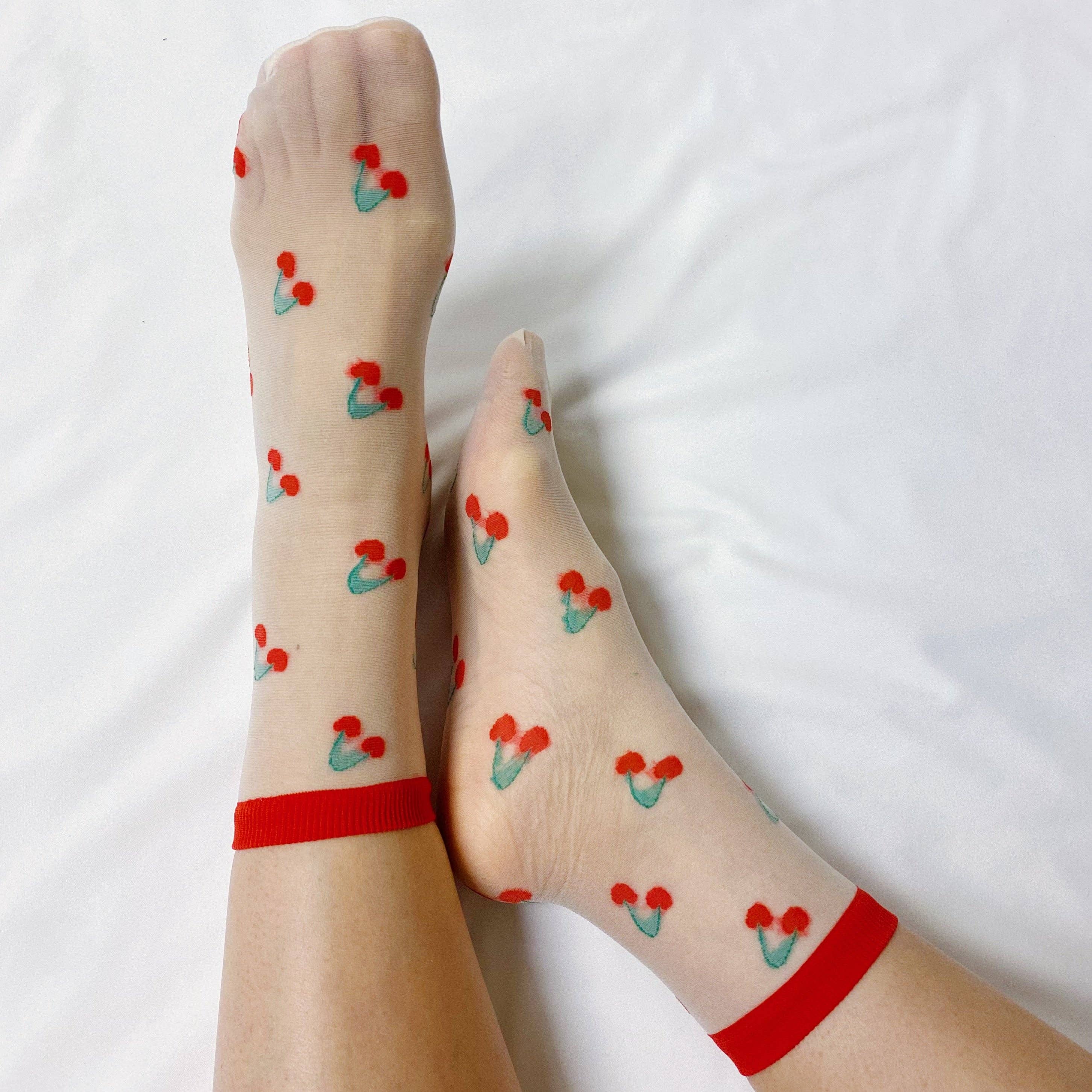 Sheer socks with cherry pattern and red bands on a white background