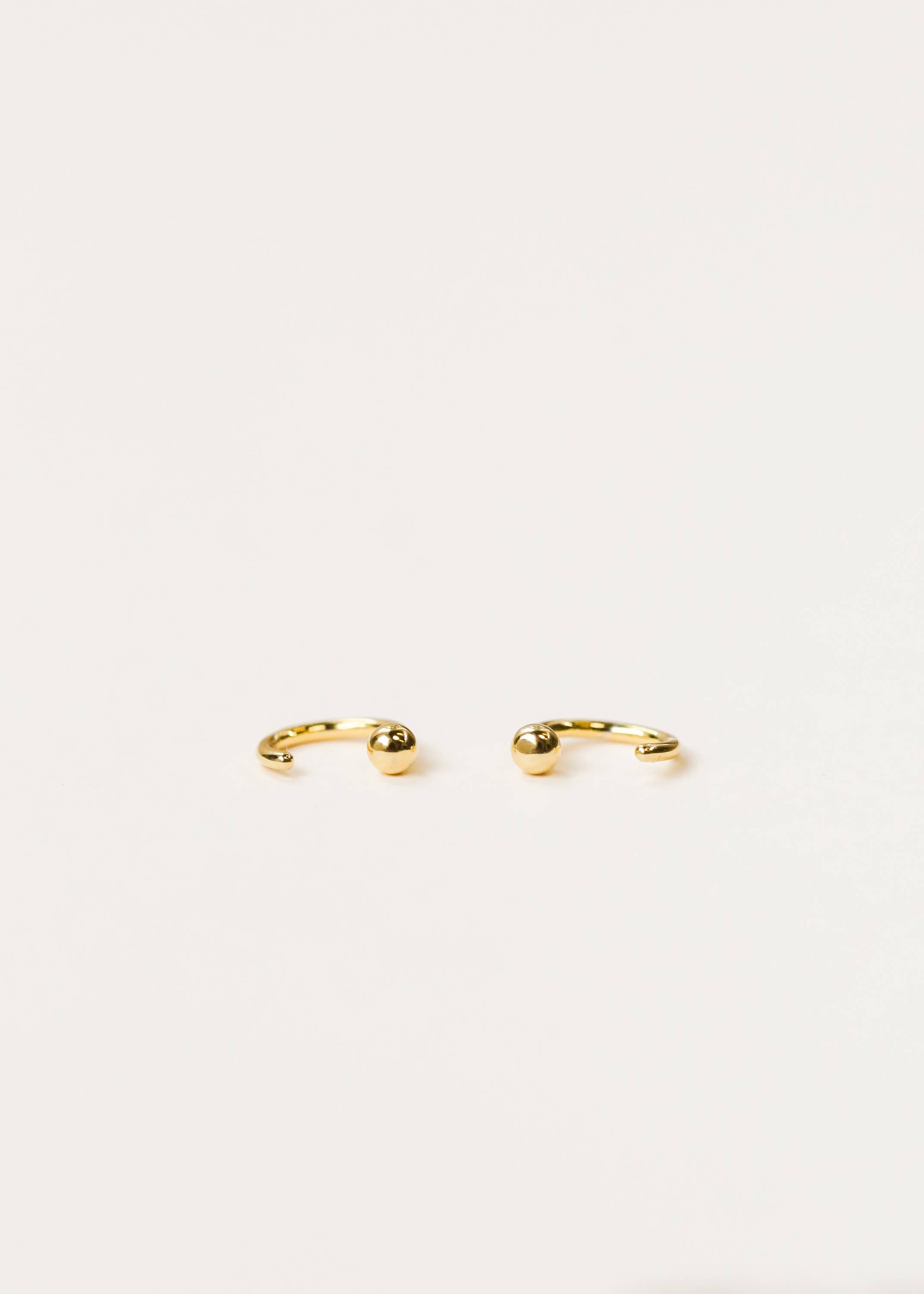Gold earrings on a light beige background