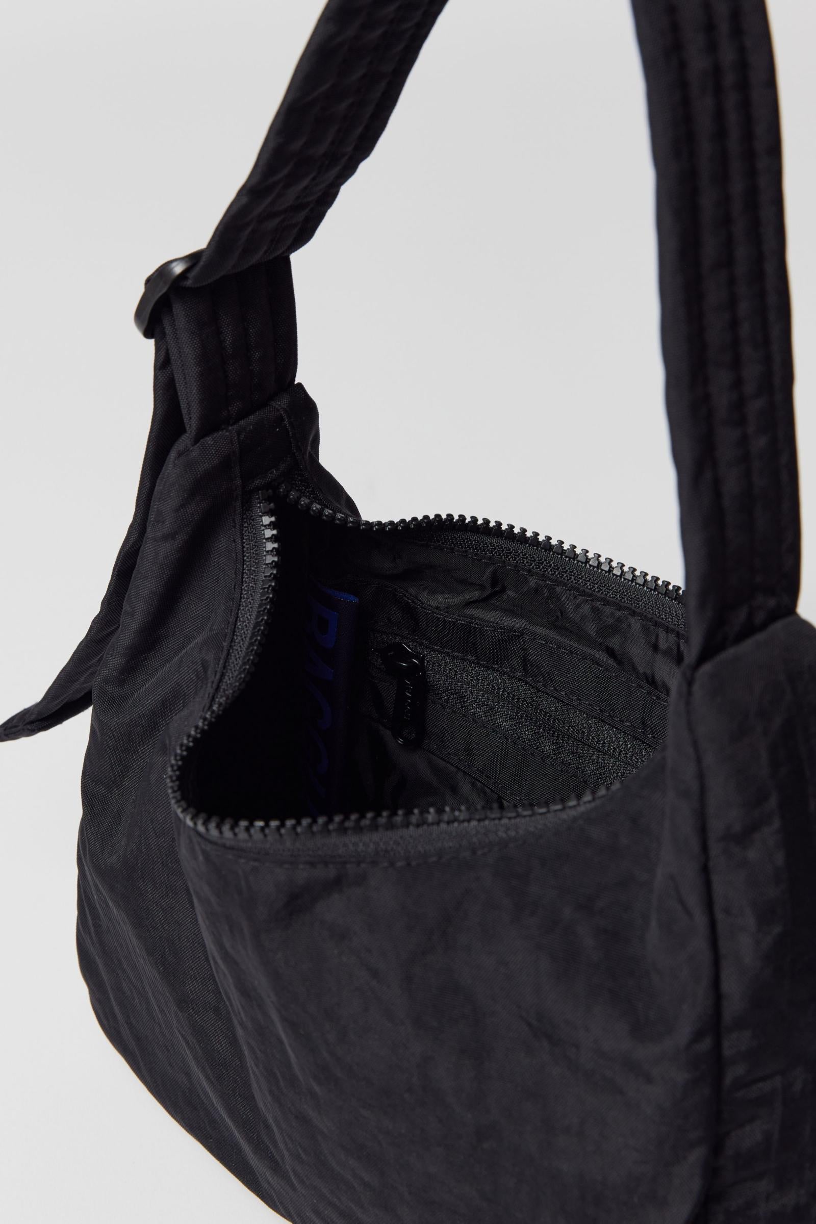 inside details of black nylon shoulder bag from BAGGU sitting on white background 