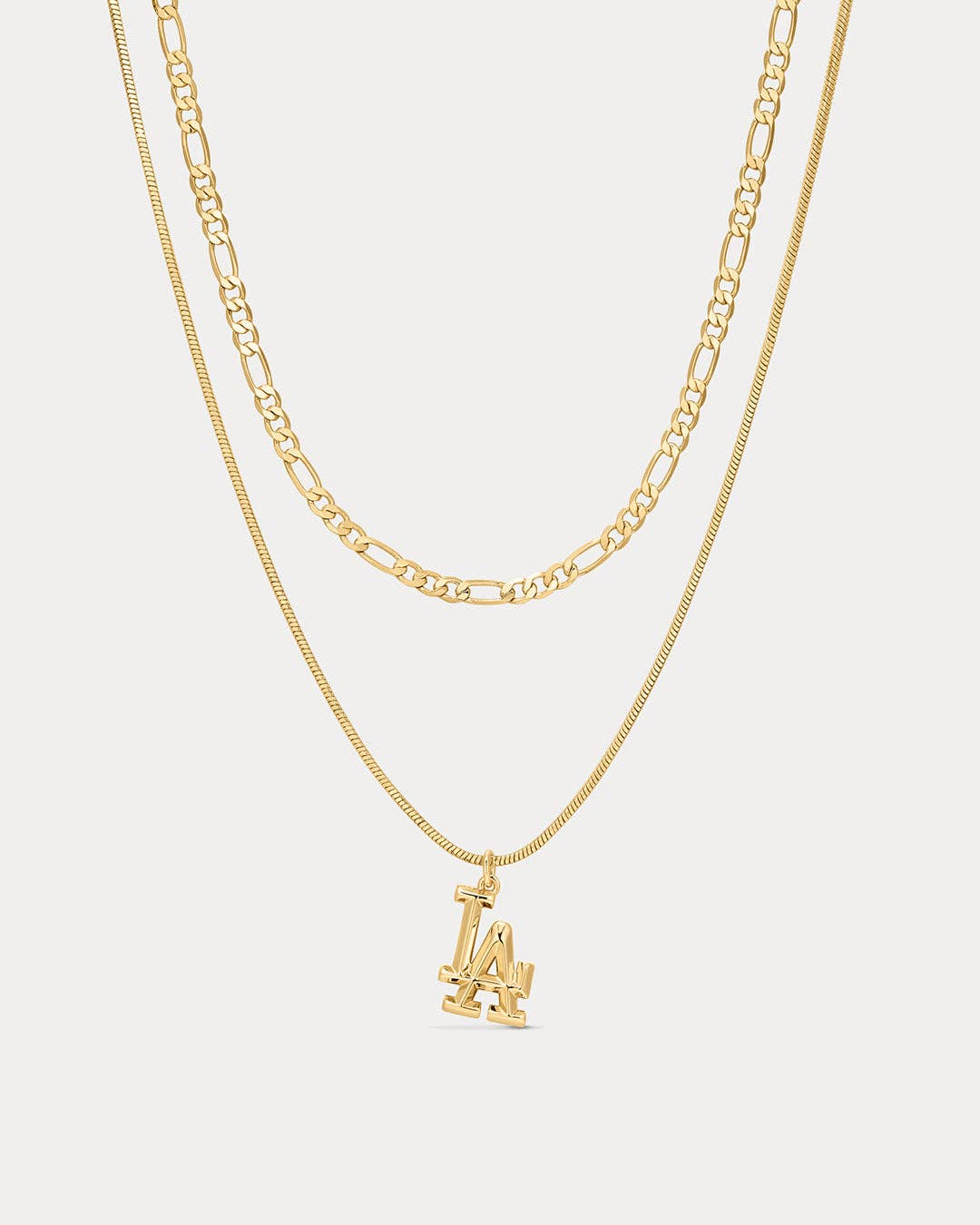 Gold necklace with a 'LA' pendant on a light gray background
