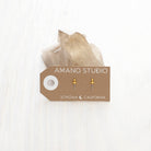 Tiny dagger stud earrings with gold handle and silver dagger shown on display card