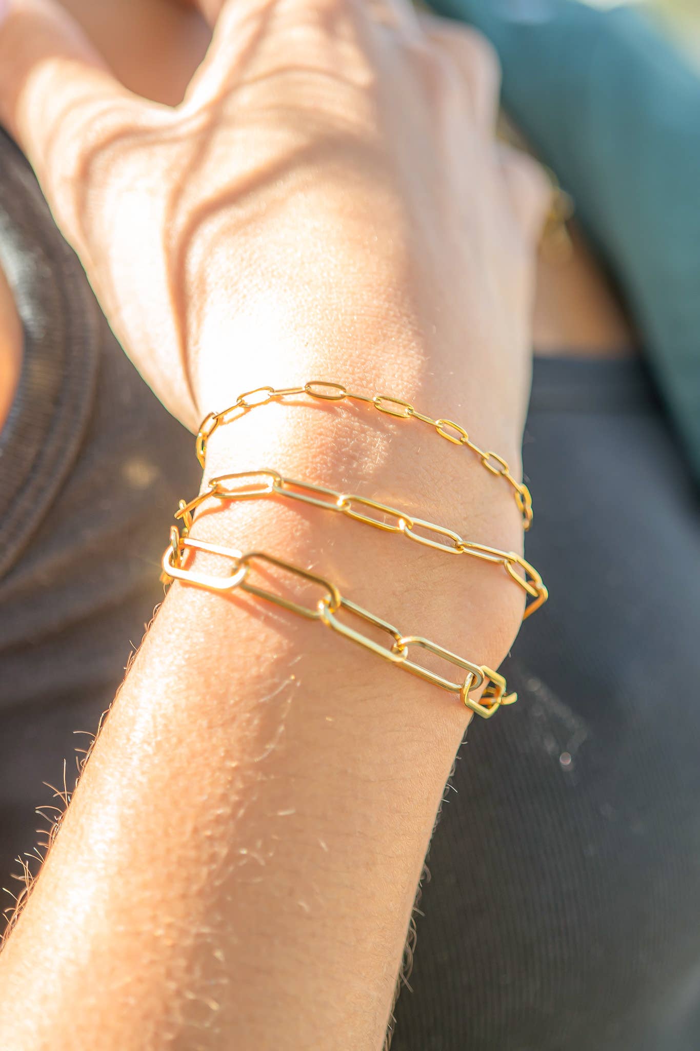 Gold chain bracelets on a wrist with a blurred background