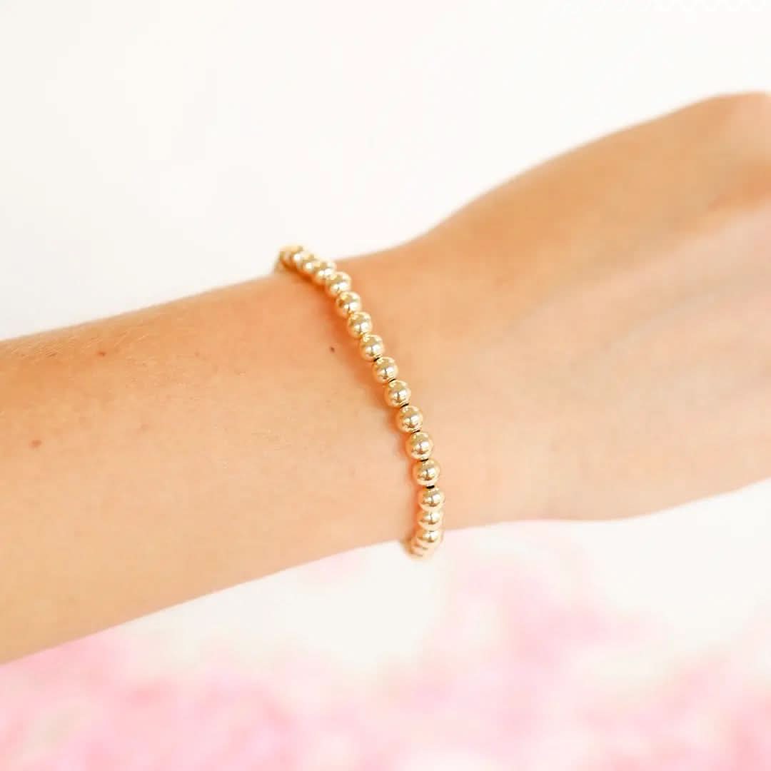 14K Gold Filled Gold beaded bracelet on a wrist with a soft pink 