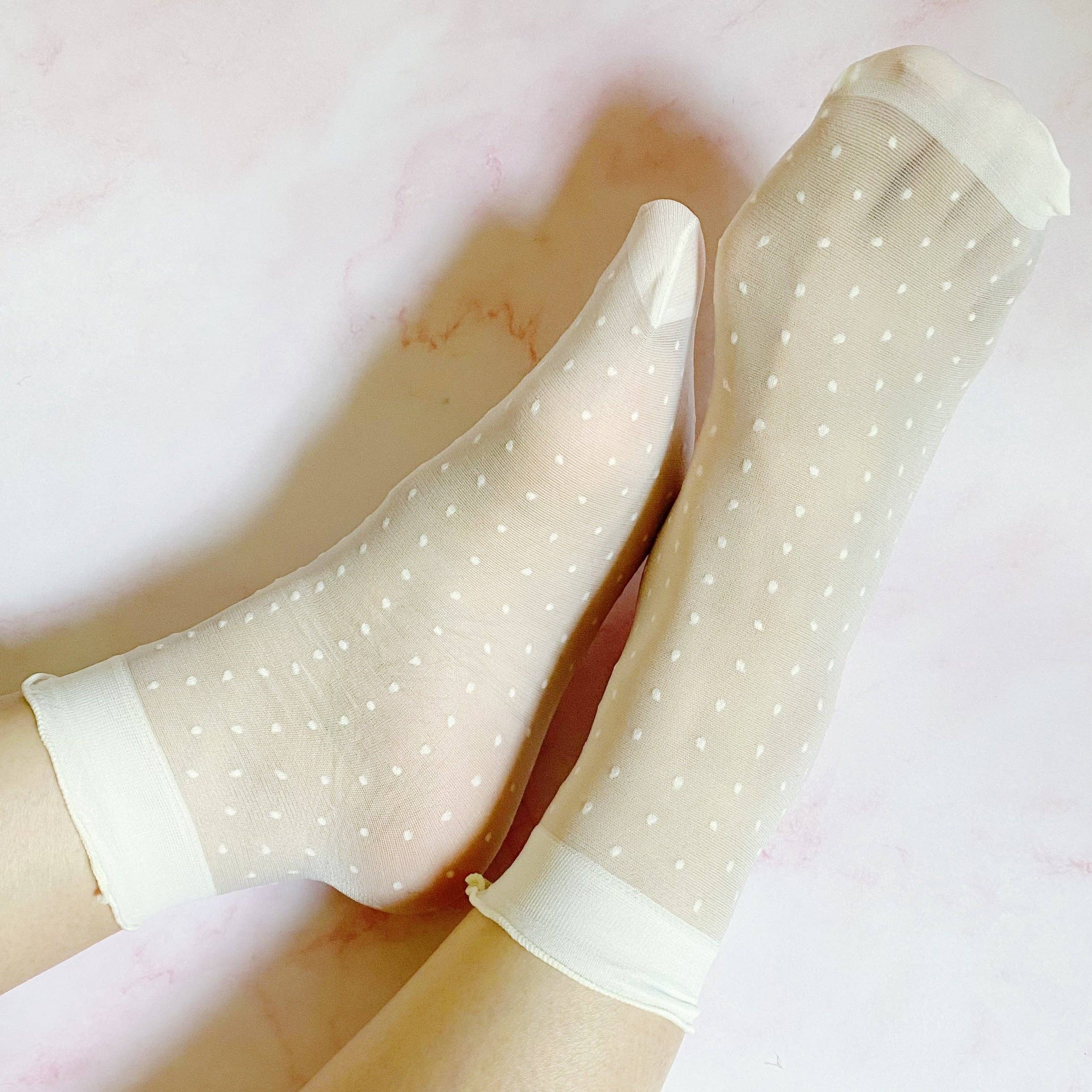 Sheer beige socks with white polka dots on a light pink background
