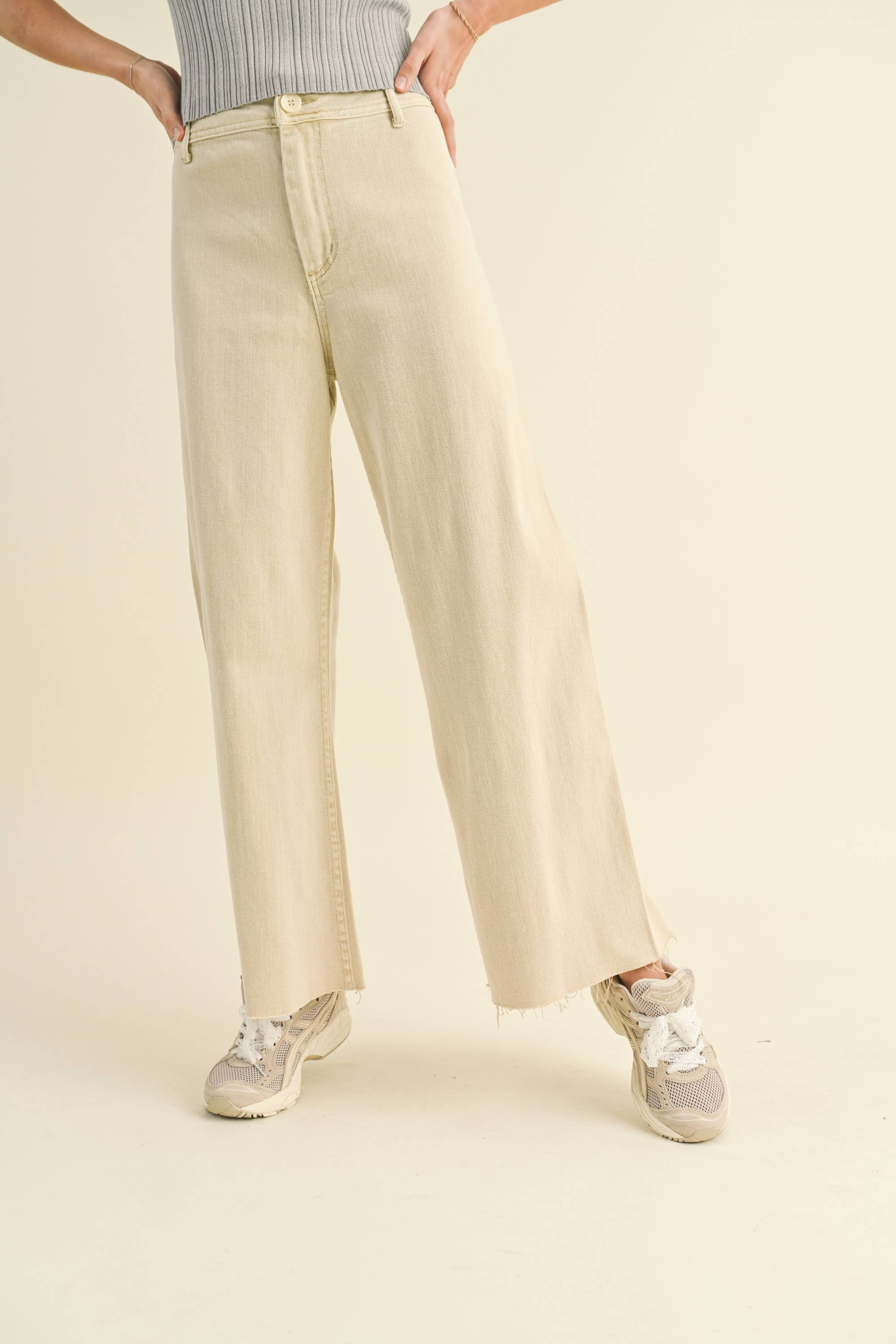 Person wearing beige pants and sneakers on a plain background