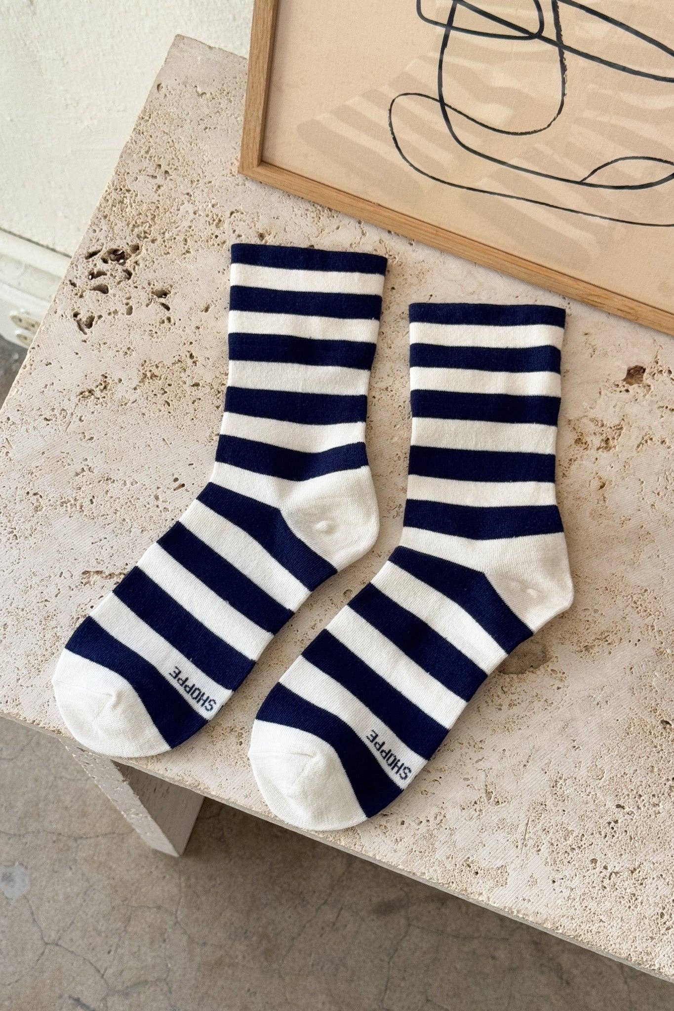 Navy and white striped socks on a textured surface with abstract art in the background