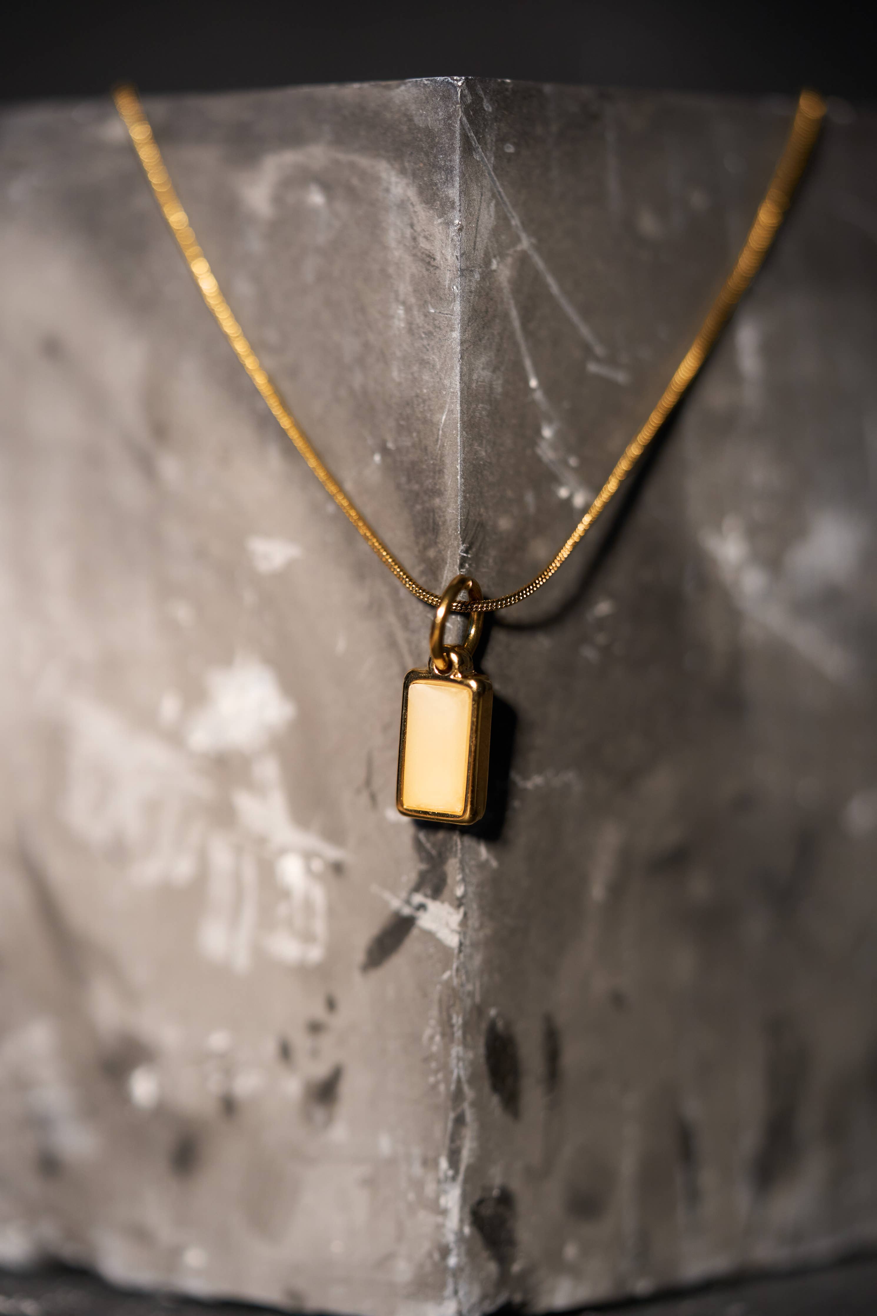 Gold necklace with a rectangular cream-colored pendant