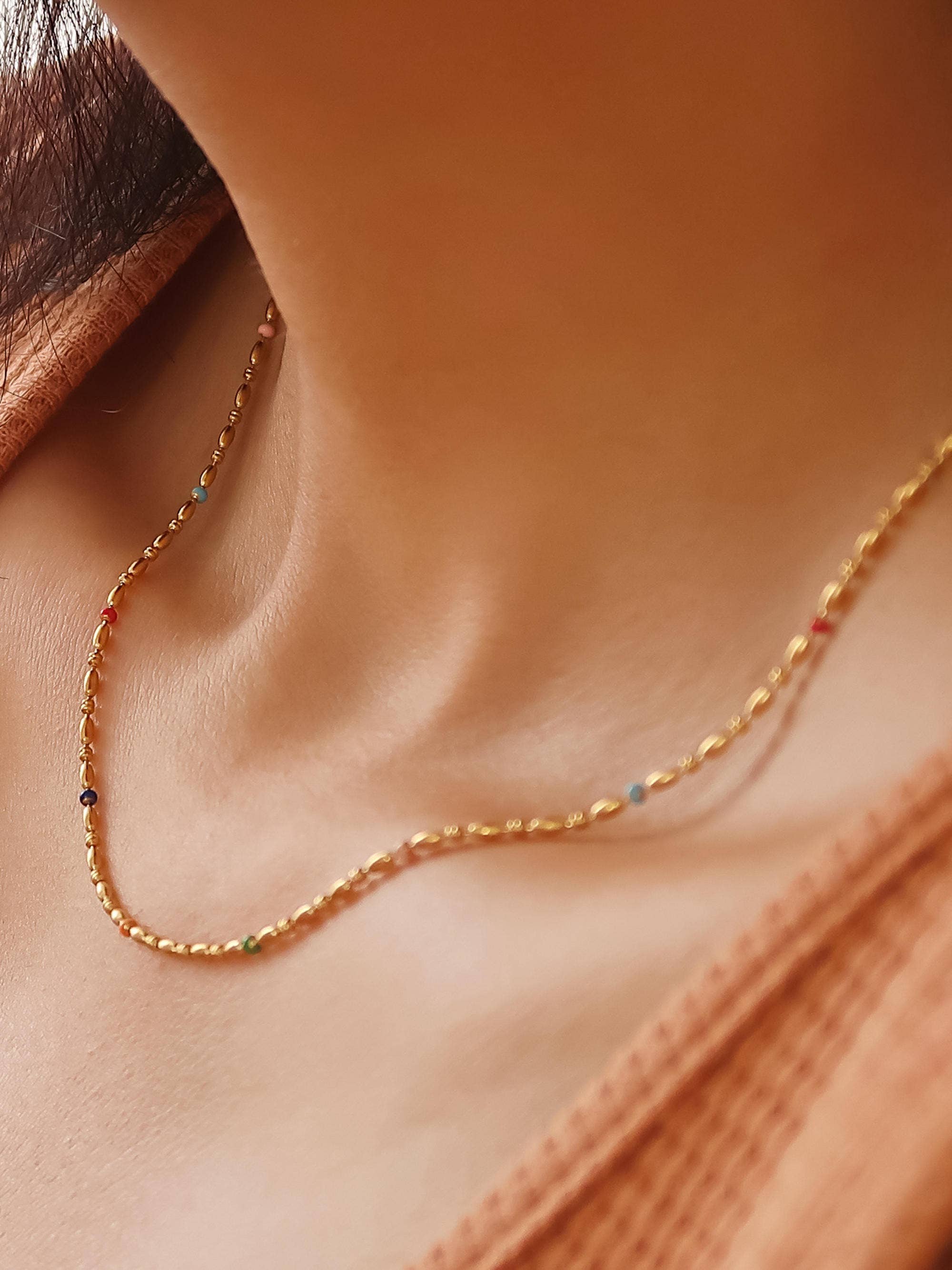 Gold necklace with small beads on a person's neck