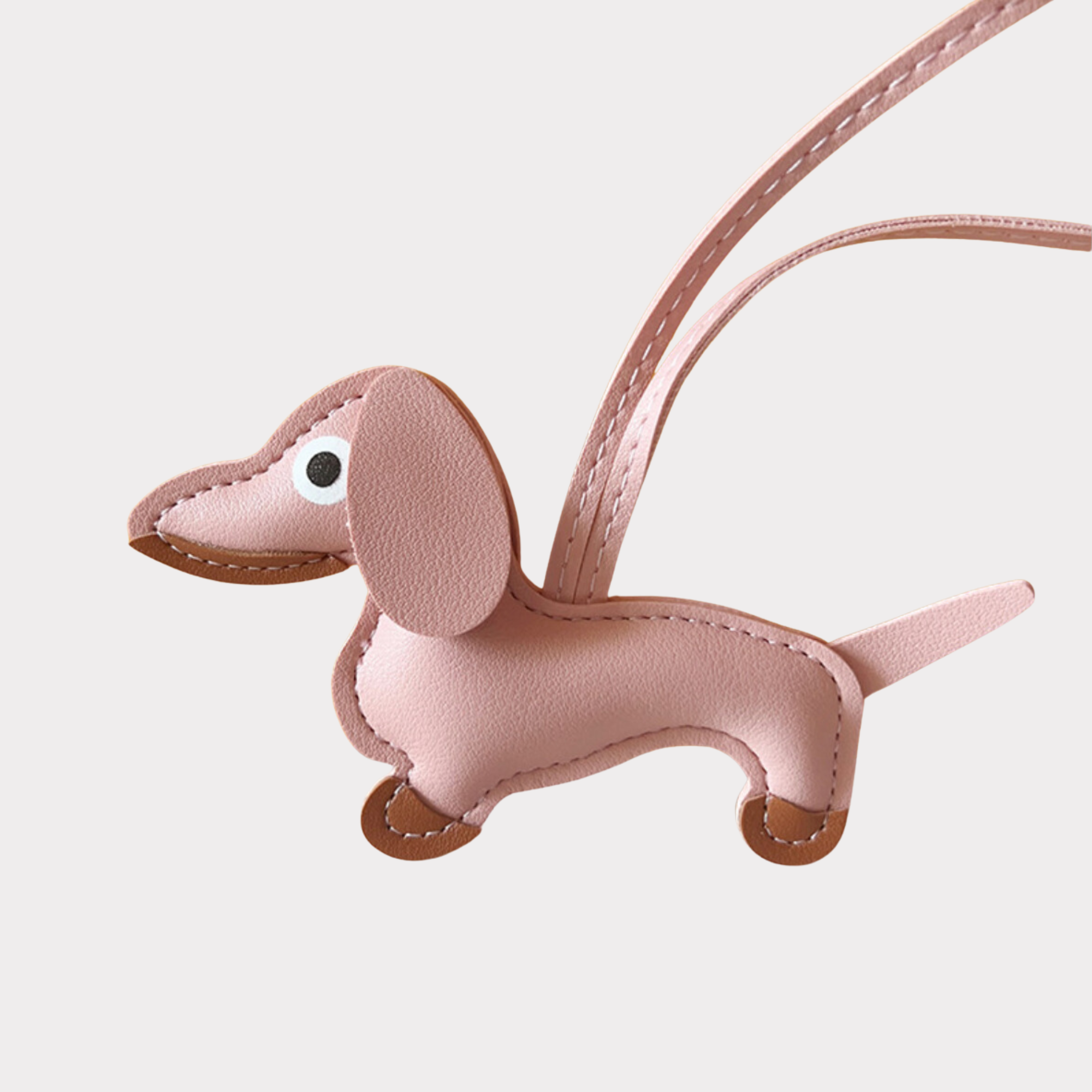 Pink washhouse dog bag charm with brown accents and pink strap on a white background. 