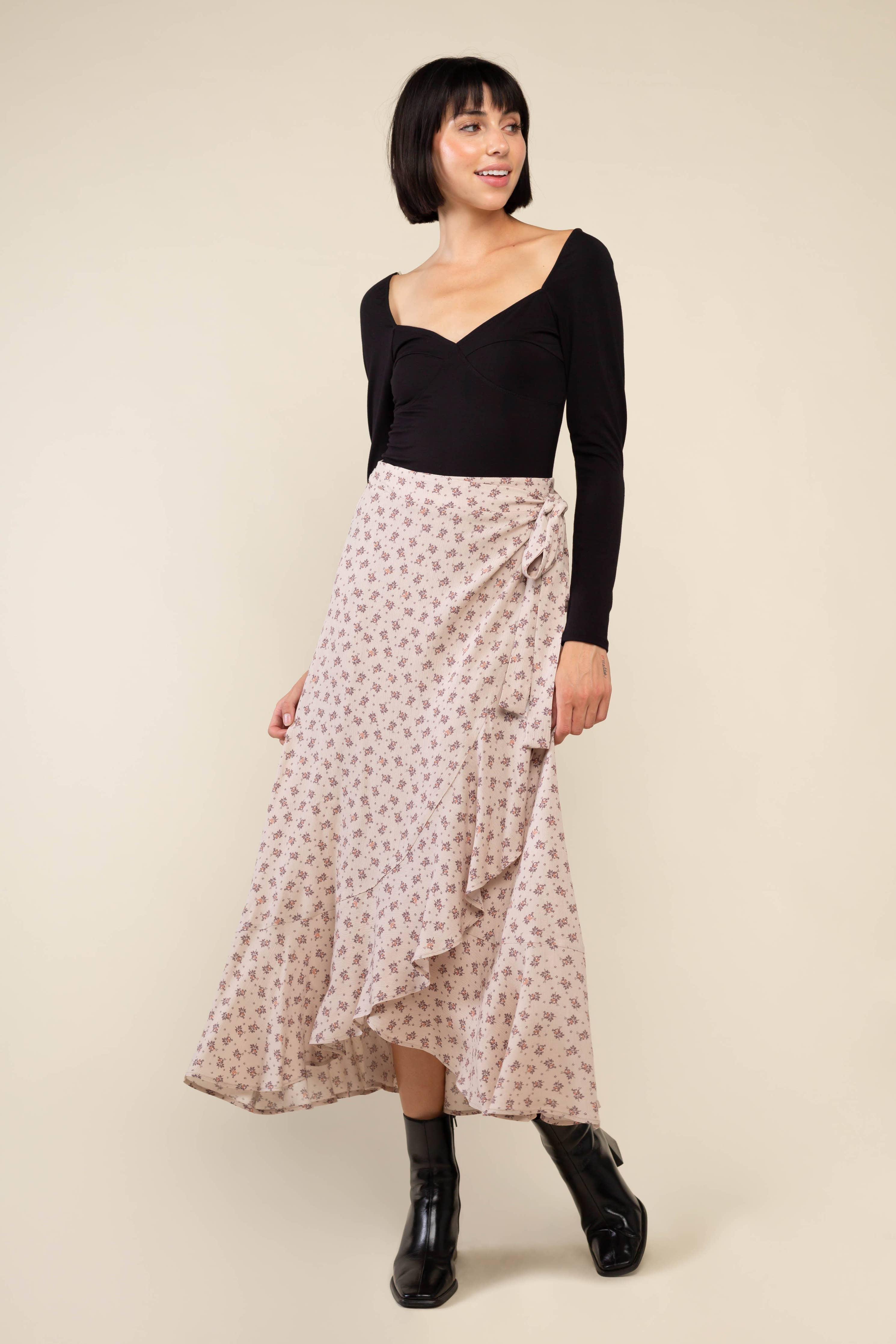 Woman wearing beige, ruffle, floral print, wrap skirt and black top 