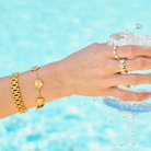 Woman wearing bracelet stack including gold watch band bracelet 
