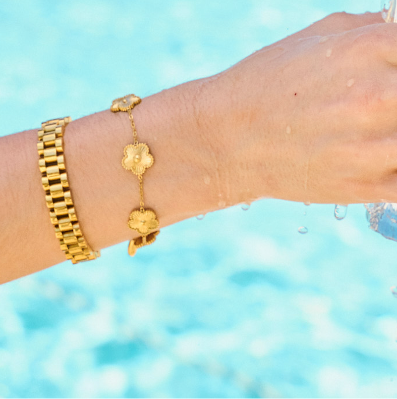 Woman wearing bracelet stack including gold watch band bracelet 