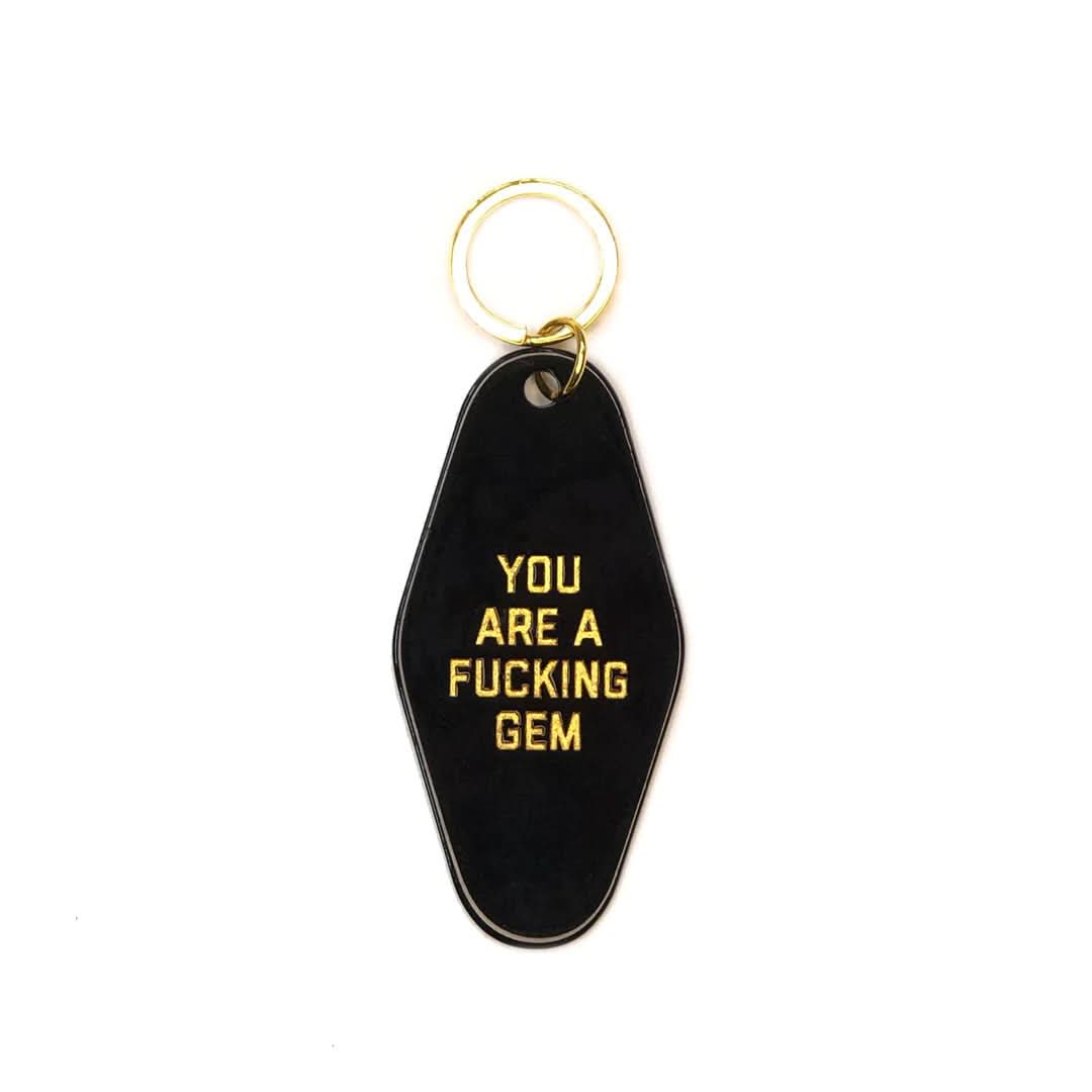 Black motel keychain that has gold letters that say You Are A Fucking Gem