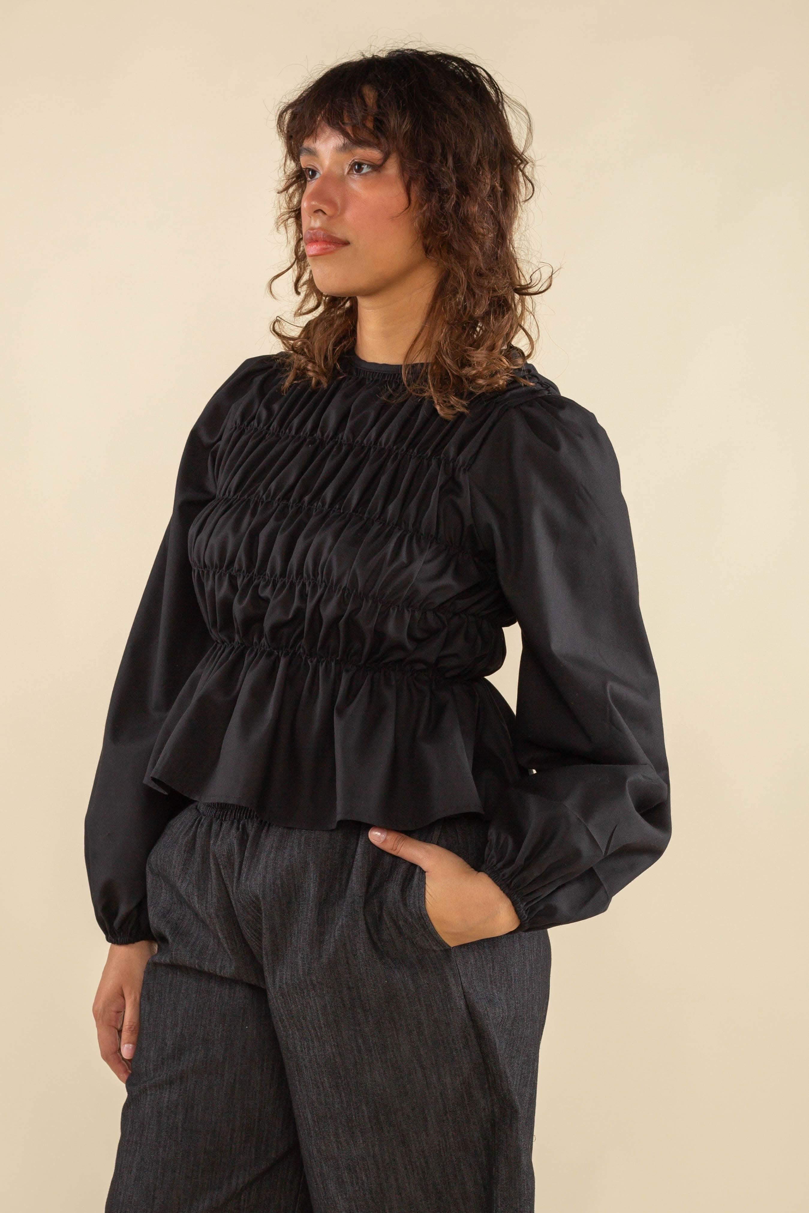 Woman wearing black, bubble long sleeve, shirred, peplum style top