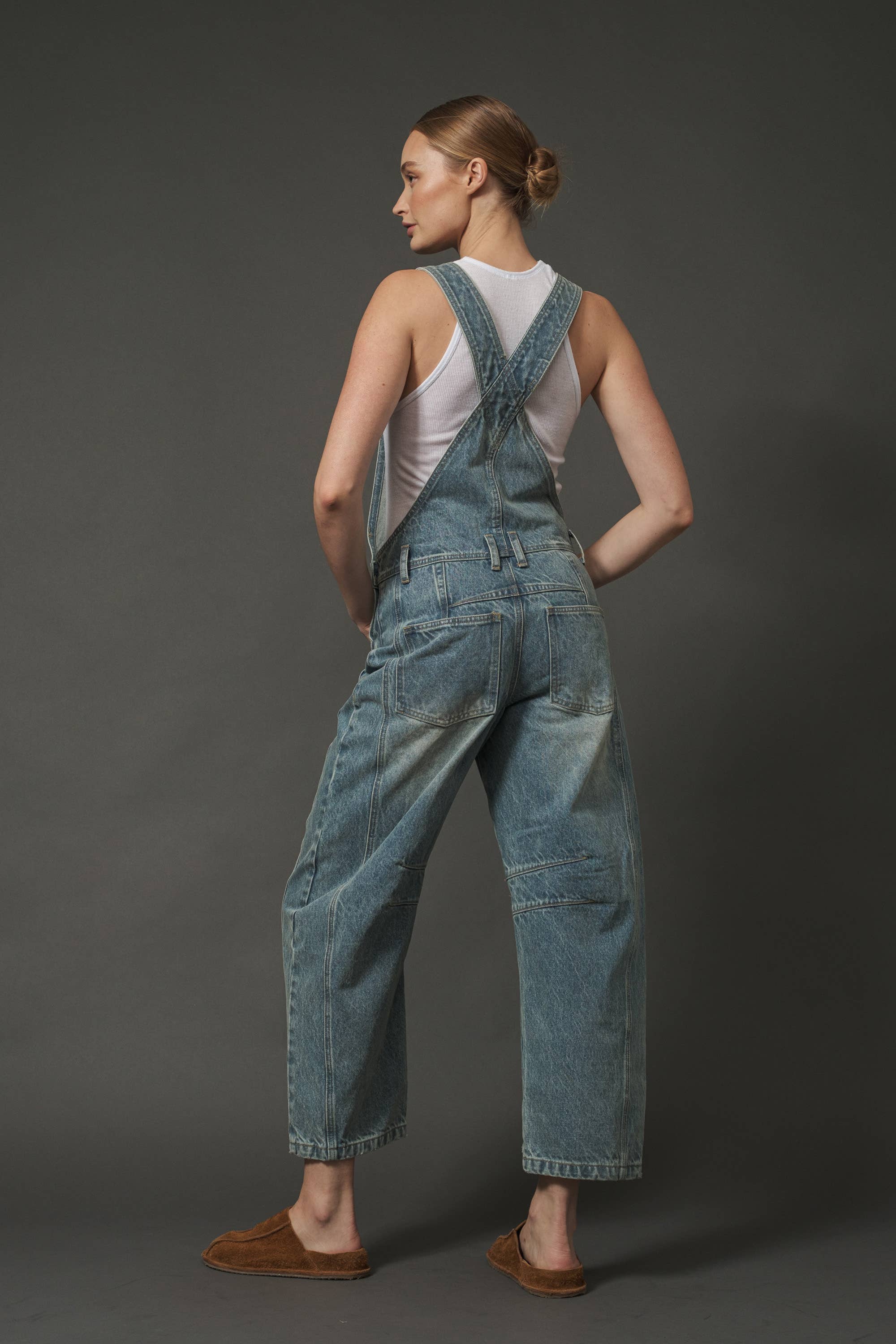Woman wearing blue denim overalls on a dark gray background