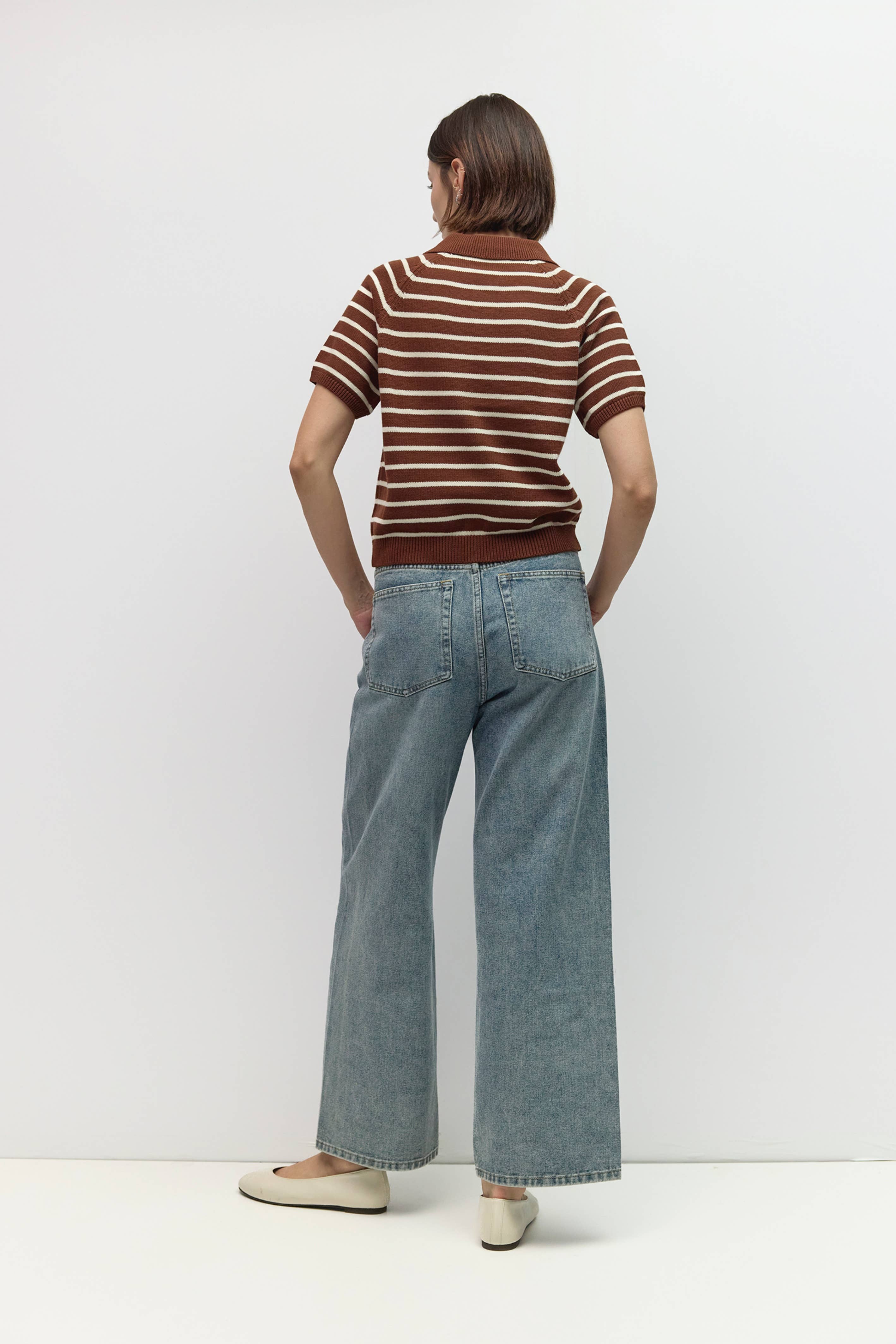 Person wearing a striped shirt and wide-leg jeans against a white background