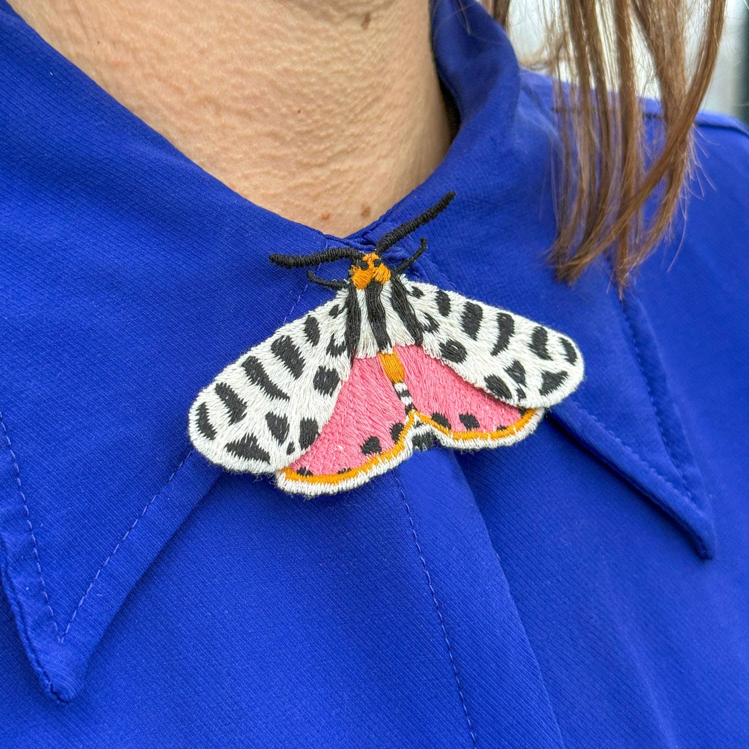 Moth-shaped brooch on a blue shirt