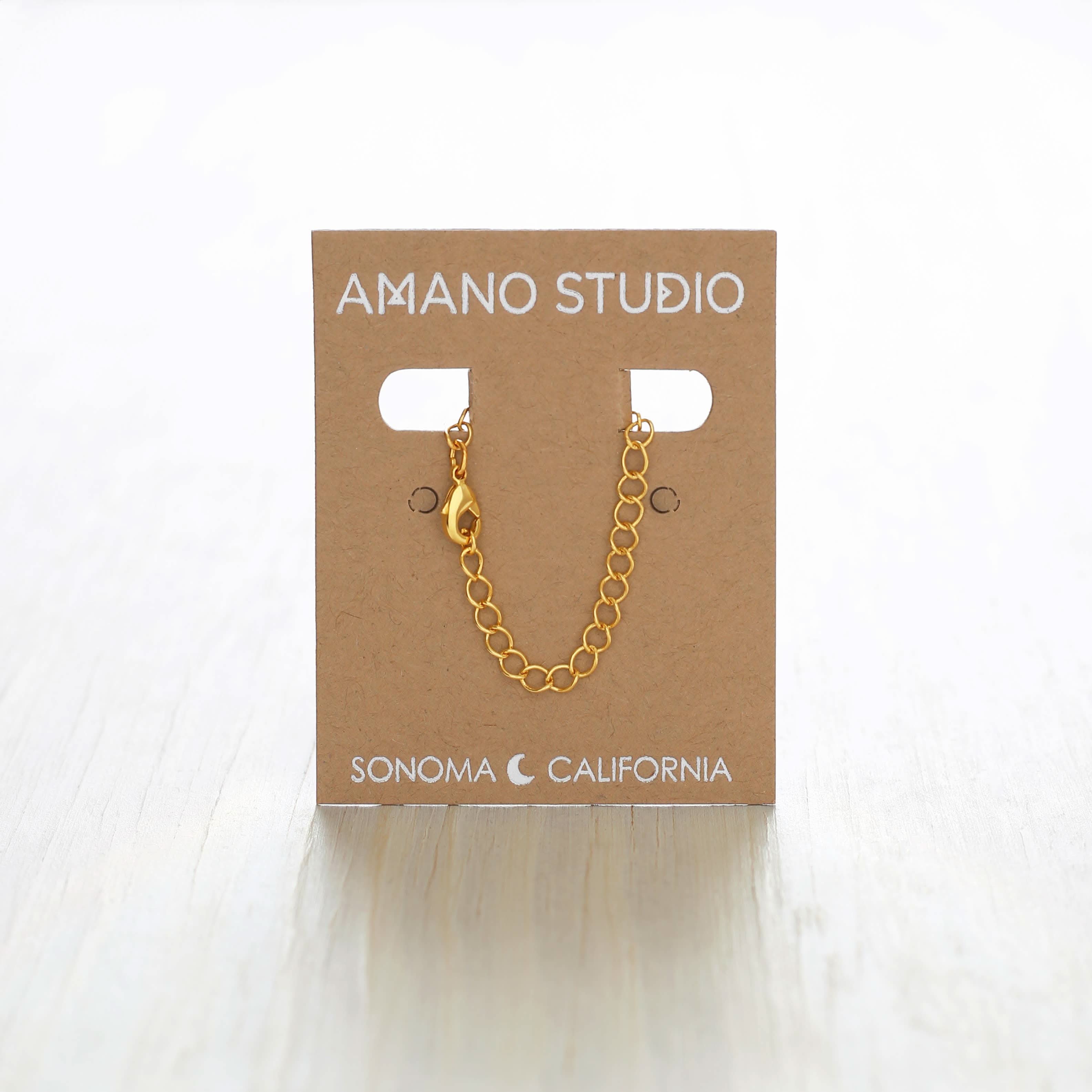 Gold chain necklace on a 'Amano Studio' branded card 