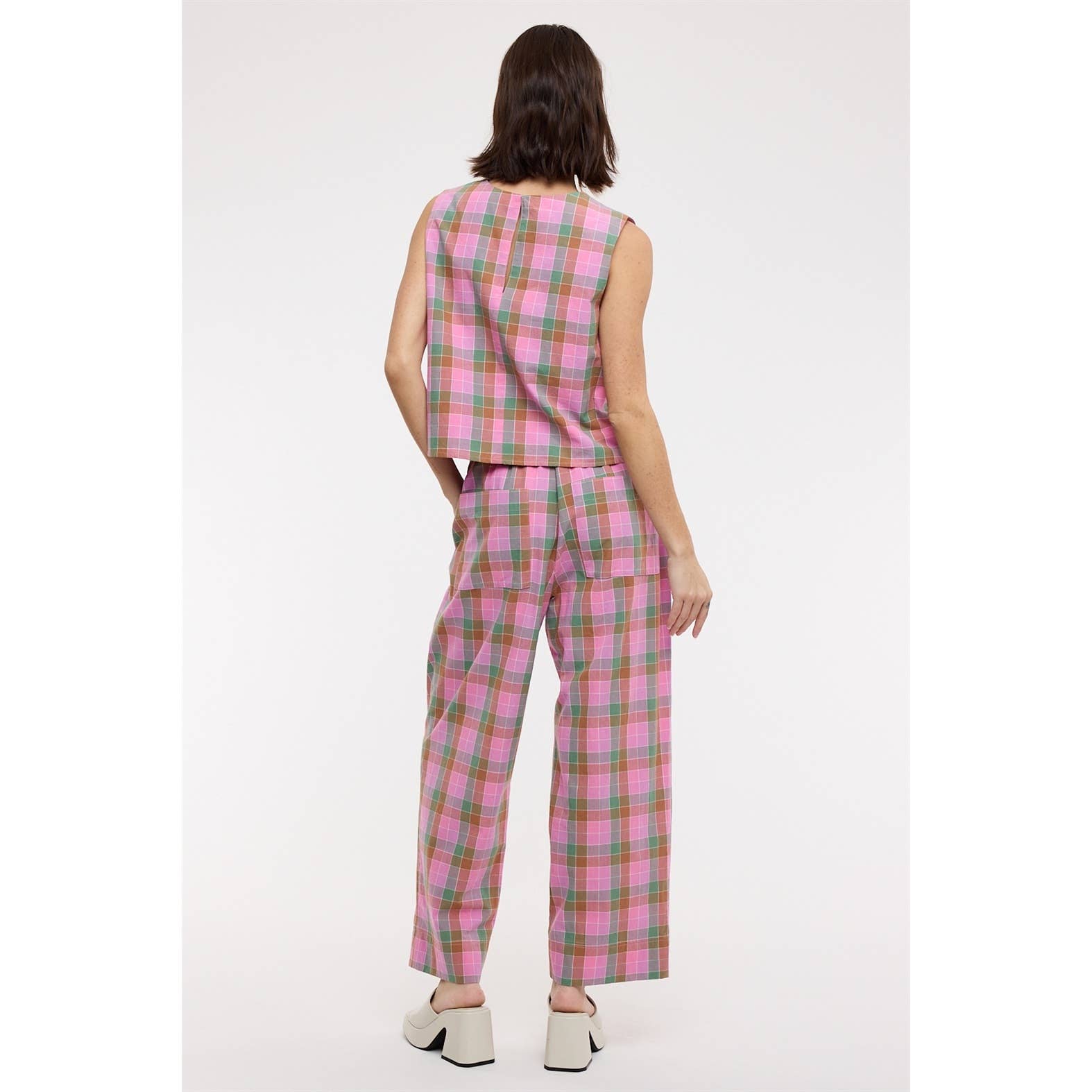 Person wearing a pink and green plaid outfit on a white background